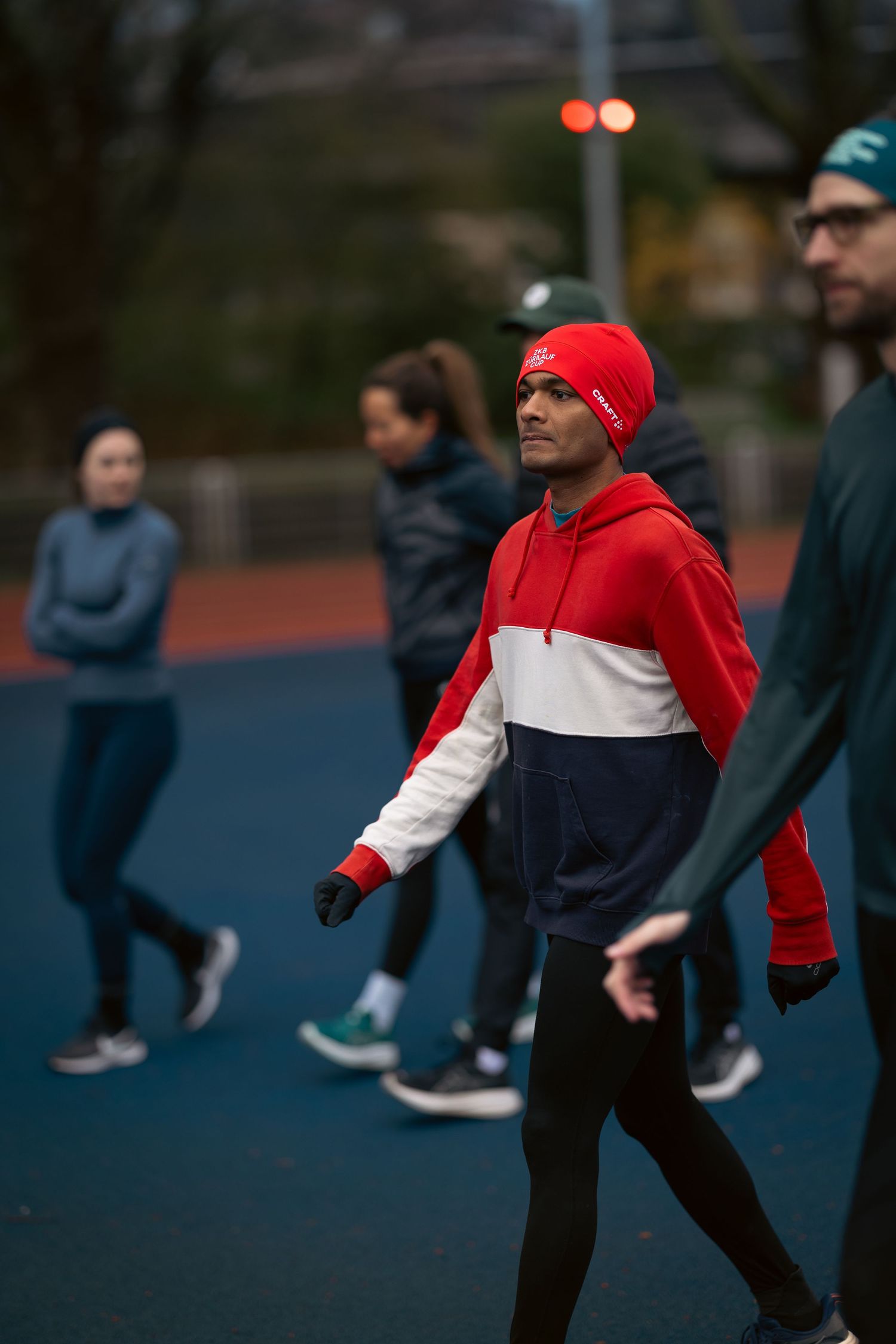 Athletes practicing dynamic stretches and warm-up exercises on a running track at dusk.