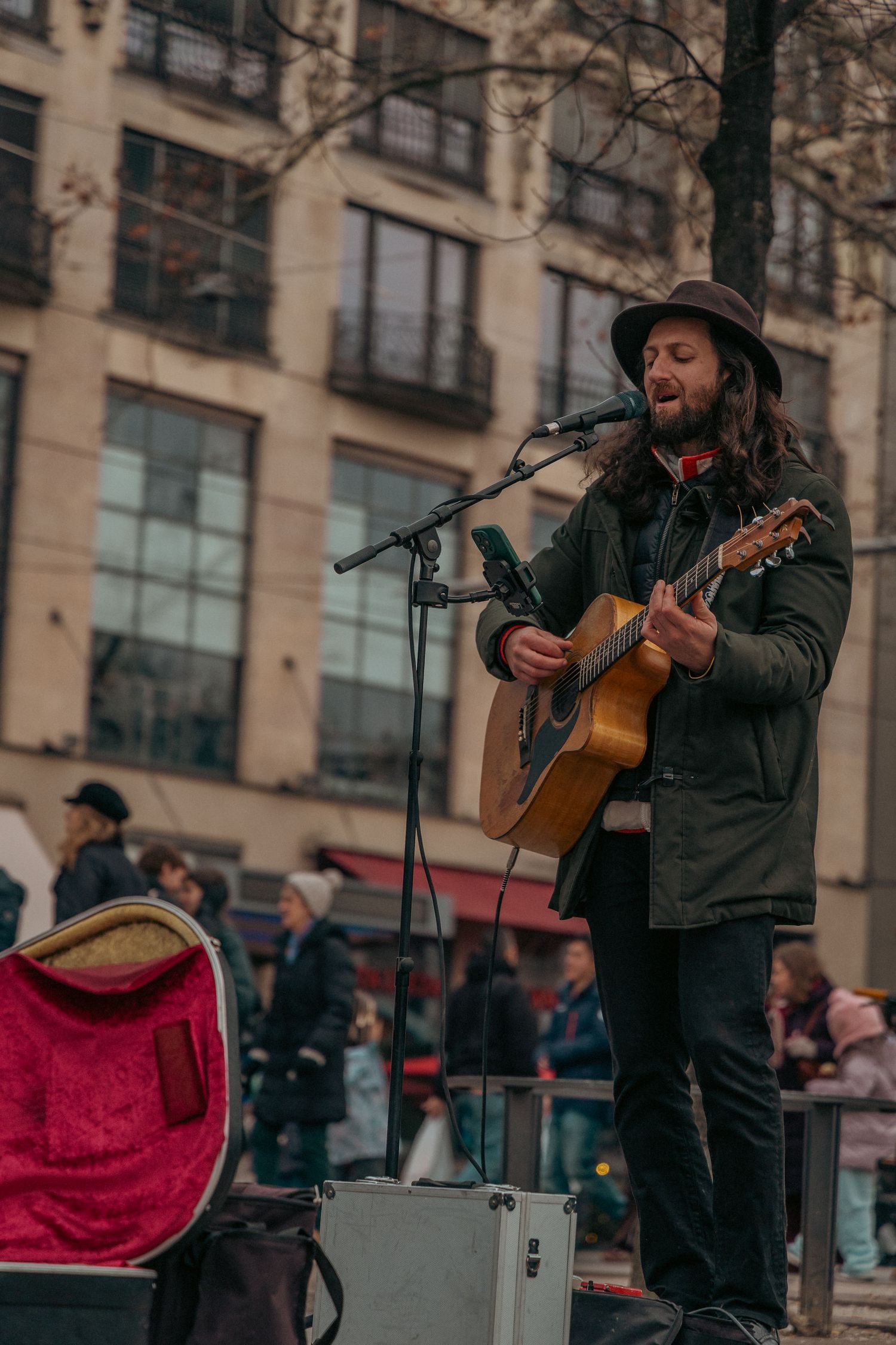 Street musician performing with guitar in front of urban buildings.