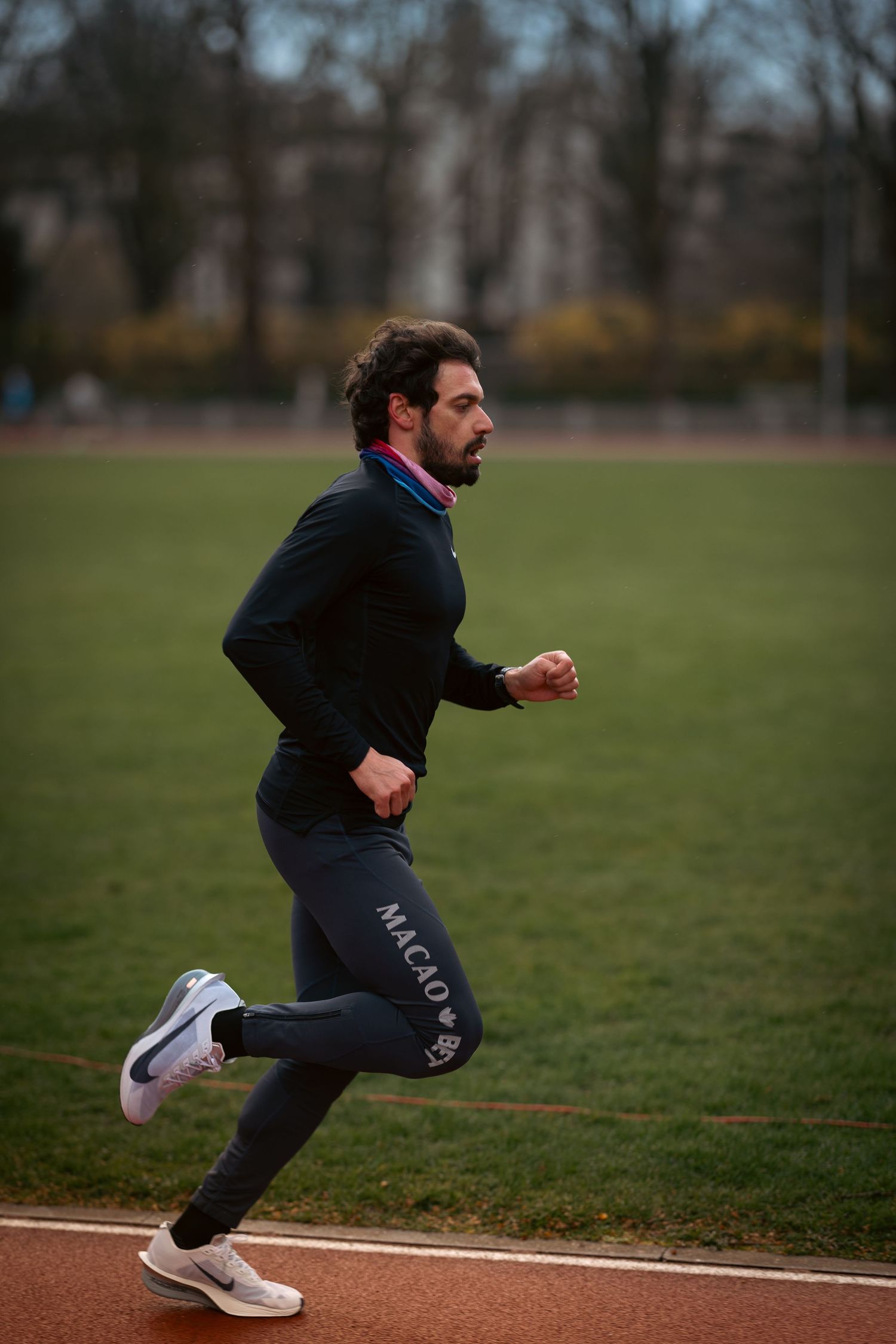 Person in dark athletic wear performing explosive running drills on a sports field.