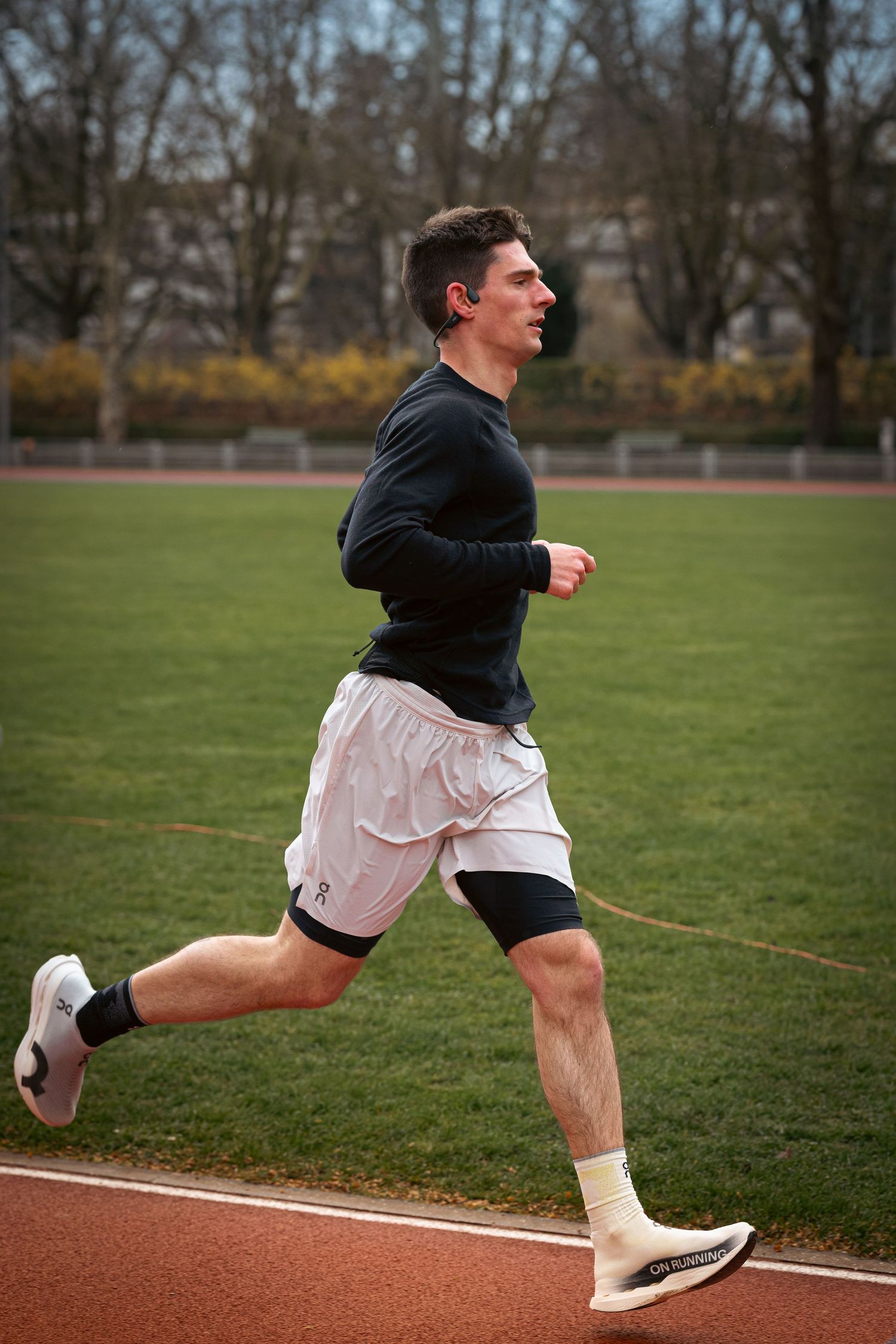 Athlete demonstrating proper running form in black shorts and top on a track field.