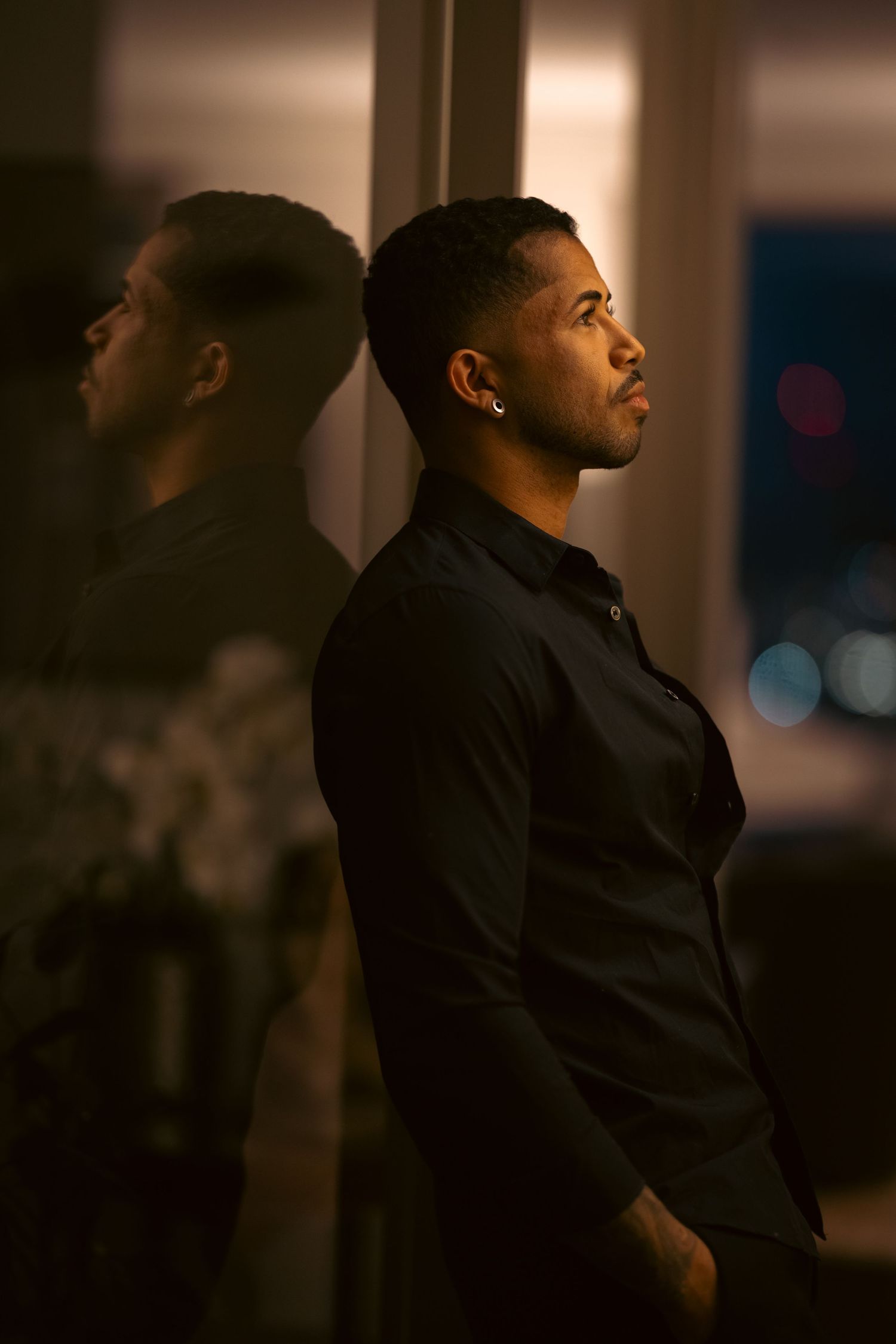 Man in black coat looking upward in dramatic lighting sequence.