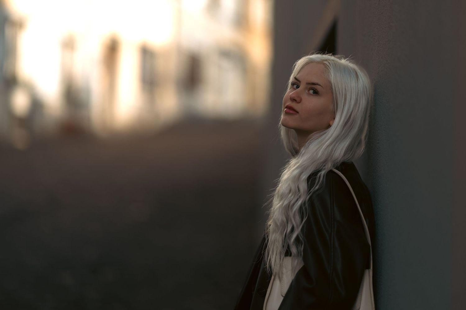 A person with long platinum blonde hair poses dramatically against a dark background in a series of moody portraits.