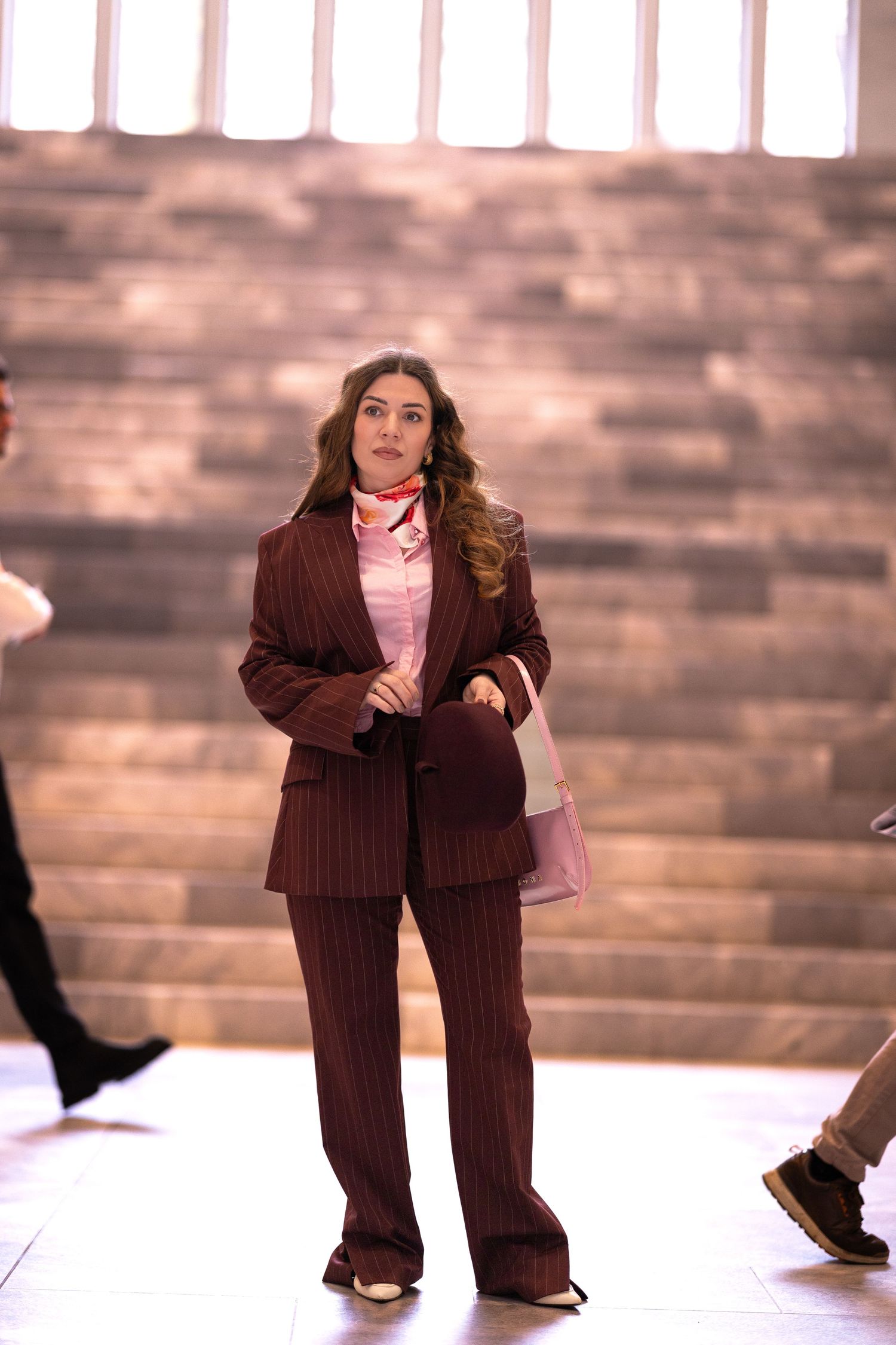 A sequence of photos showing a person in a brown pinstripe suit and pink shirt dancing across a white stage.
