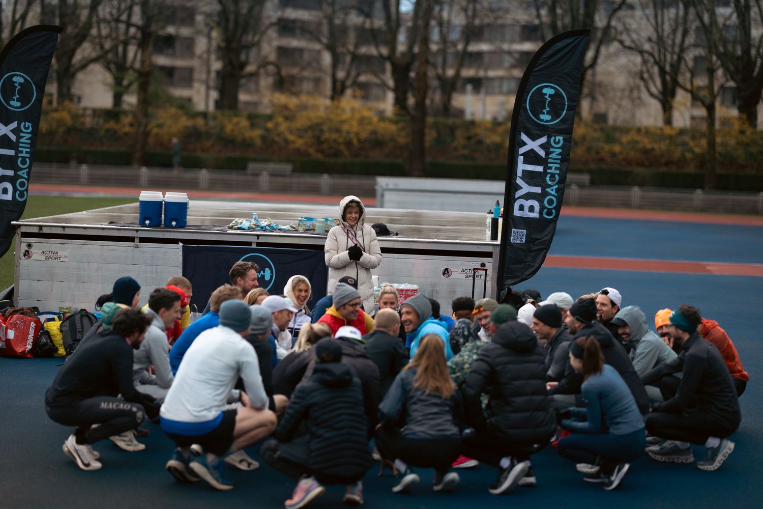 Group of runners stretching and warming up together on a track field.