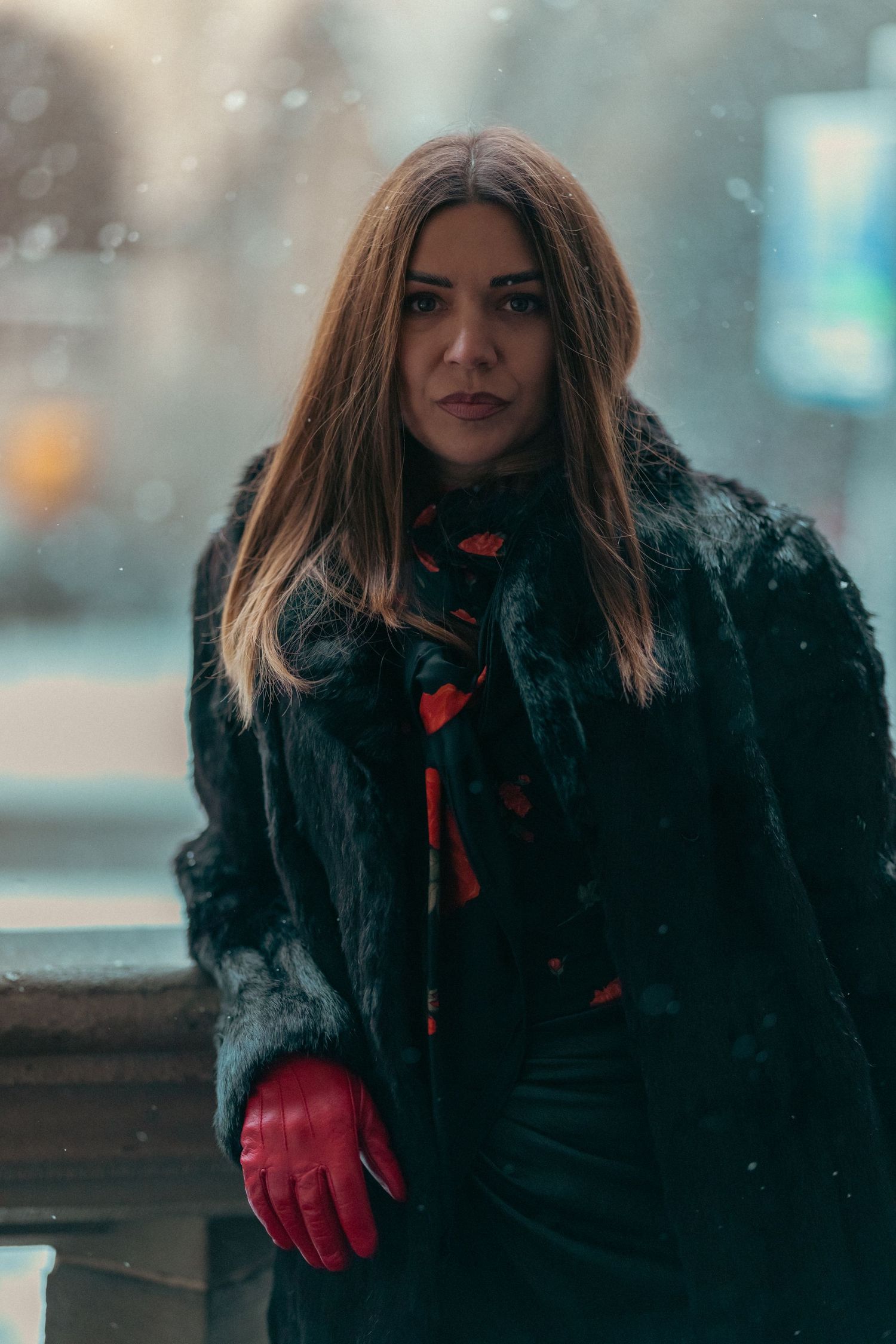 Person in black winter coat with red gloves posing in snowy weather.