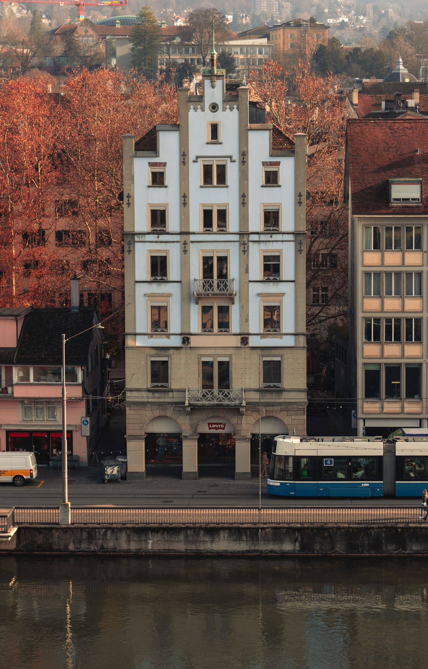 Historic white buildings with ornate architecture along a waterfront during autumn.