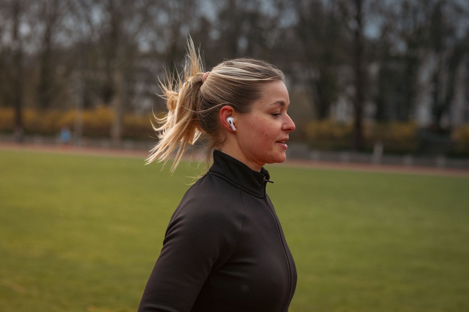 Athletic figure running on outdoor track during autumn training session.