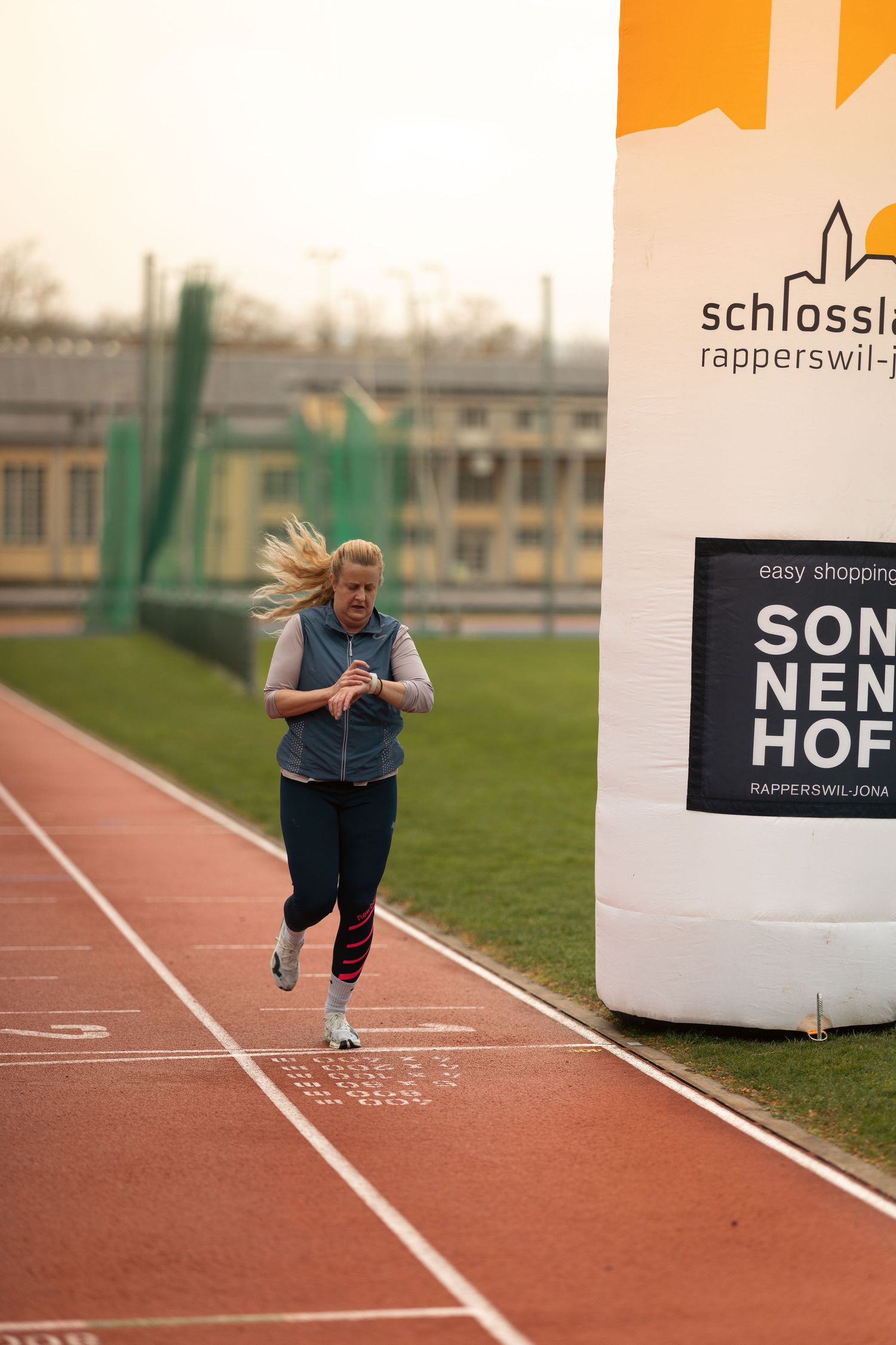 A sequence of five photos showing a person running on a red athletic track next to signage.