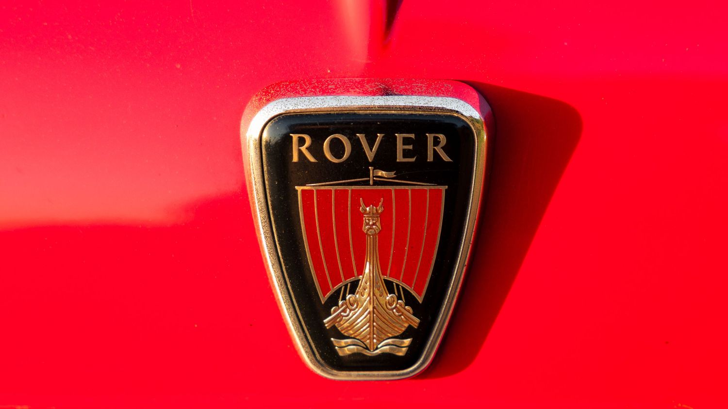 A collection of vintage car manufacturer logos displayed on a bright red background.