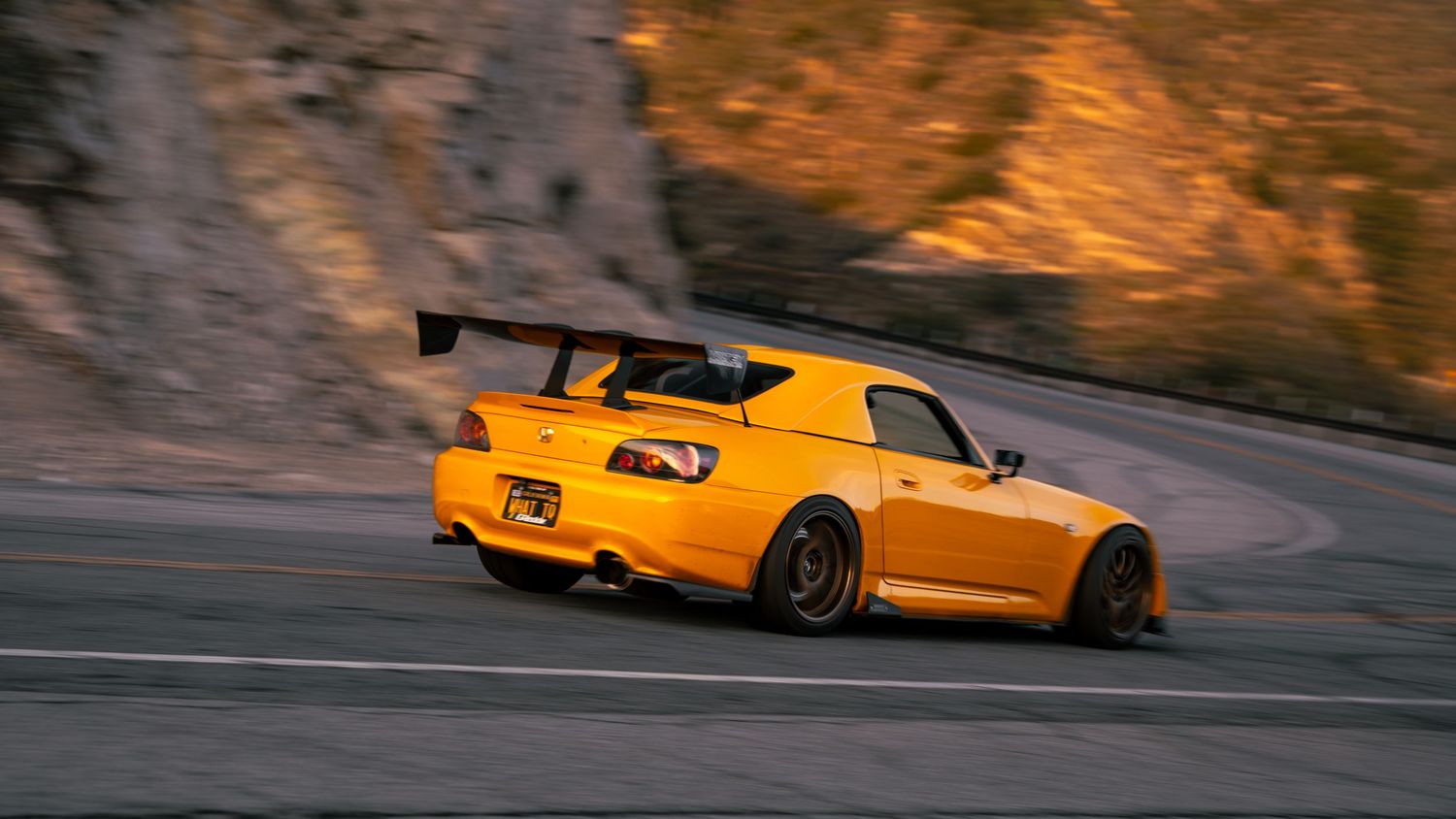 Yellow sports car drifting on a mountain road at dusk.