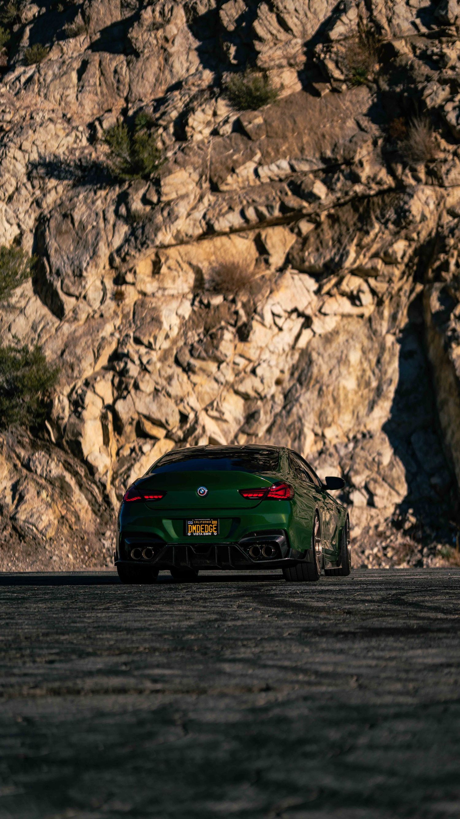 Low angle view of performance cars against rugged mountain cliffs at dusk.