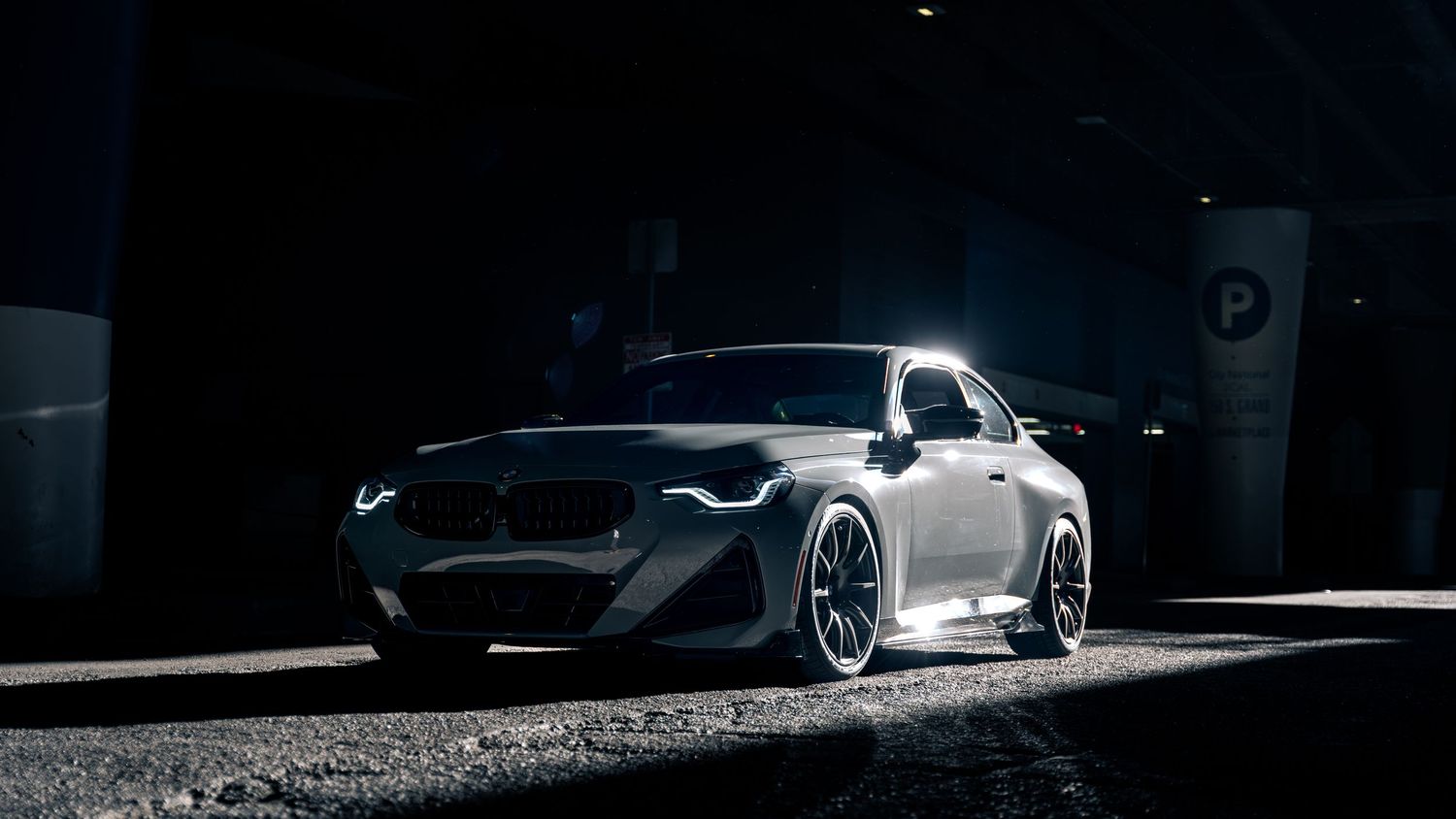 Modified sports car with custom wheels illuminated in dramatic low-key lighting.