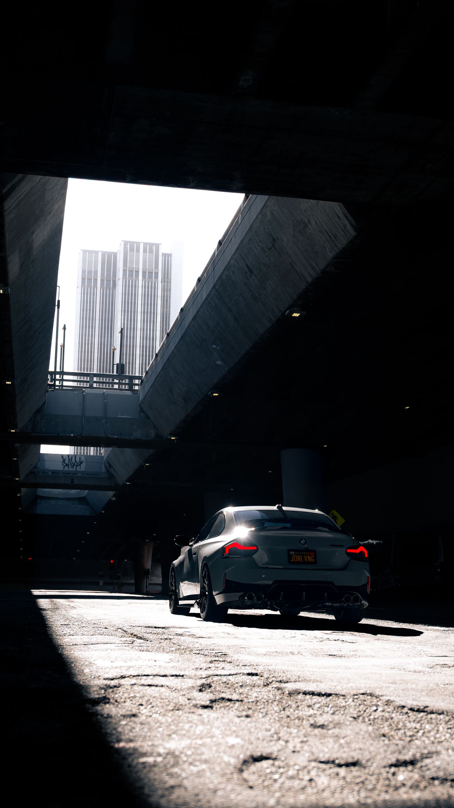 BMW vehicle photographed in dramatic lighting under an urban parking structure.