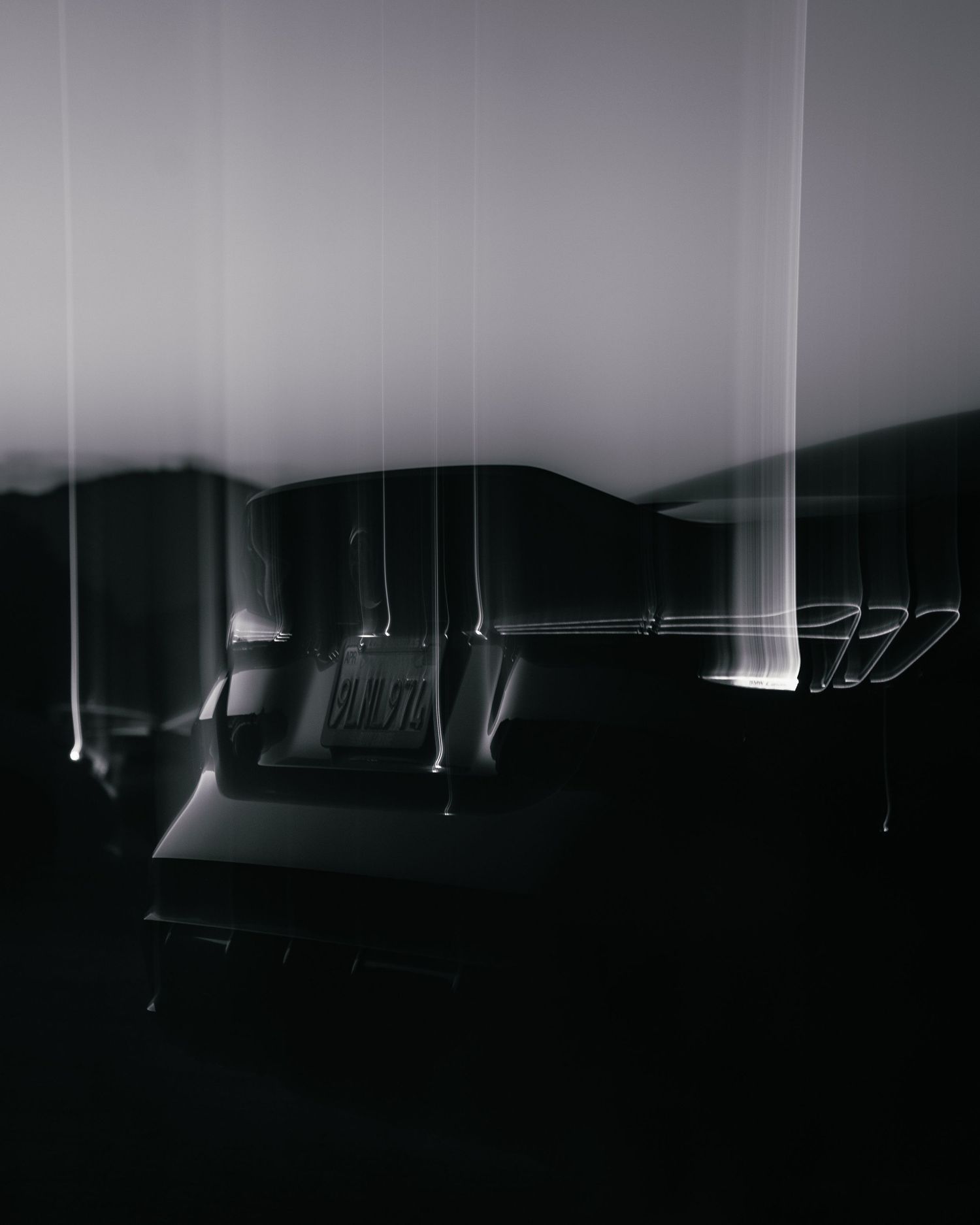 Dark silhouettes of hanging industrial lights create dramatic shadows against a monochromatic background.
