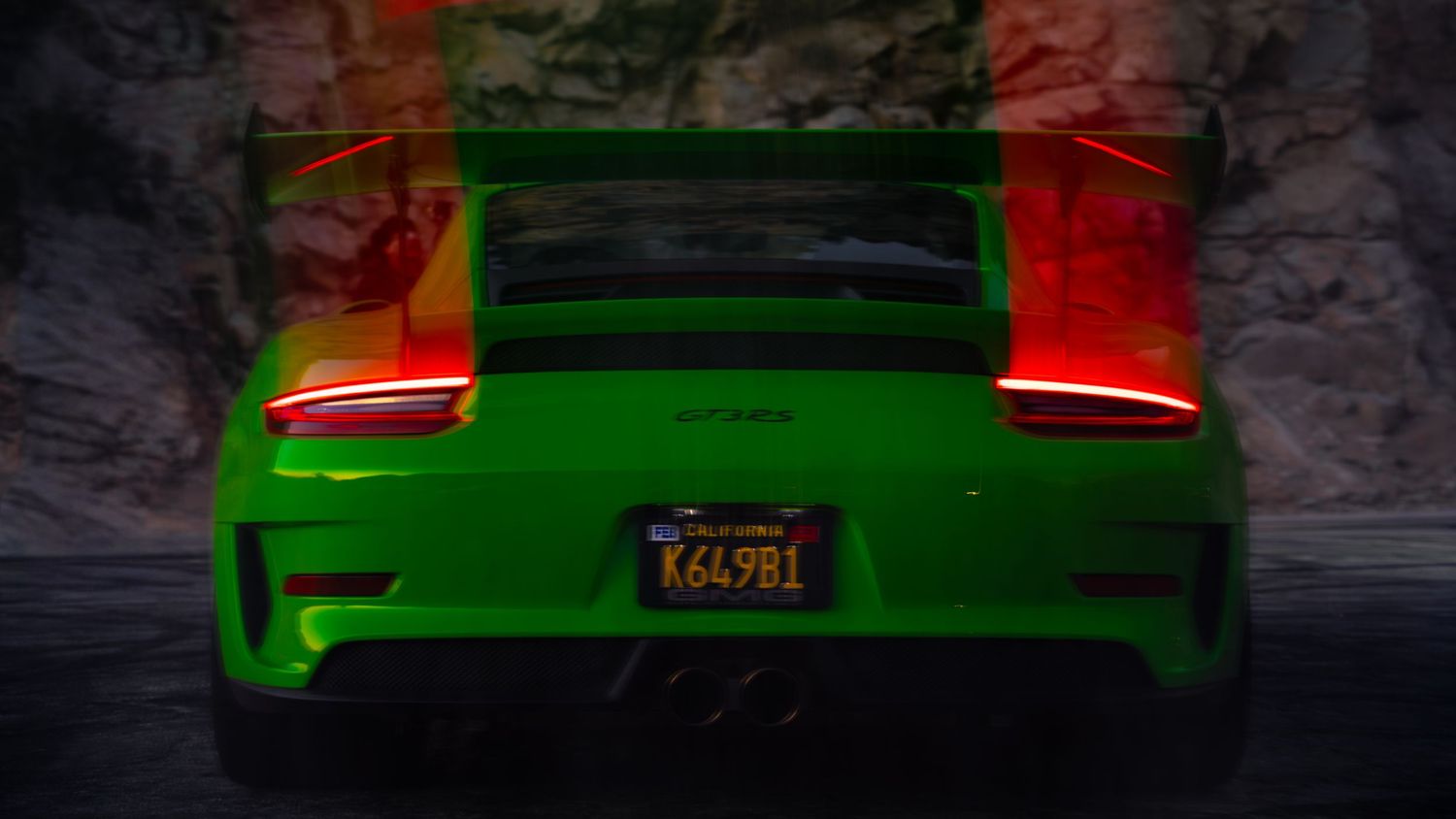 Rear view of a bright green Porsche 911 GT3 RS with glowing taillights in dark tunnel.