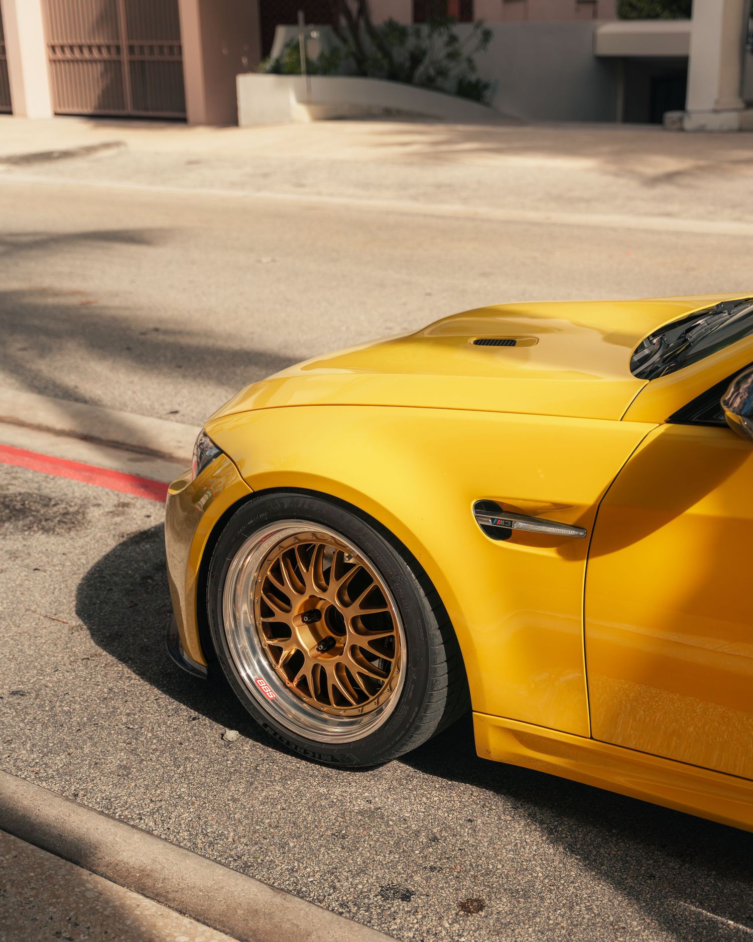 Yellow sports car with gold BBS wheels parked on street, showcasing wide body kit and aggressive stance.