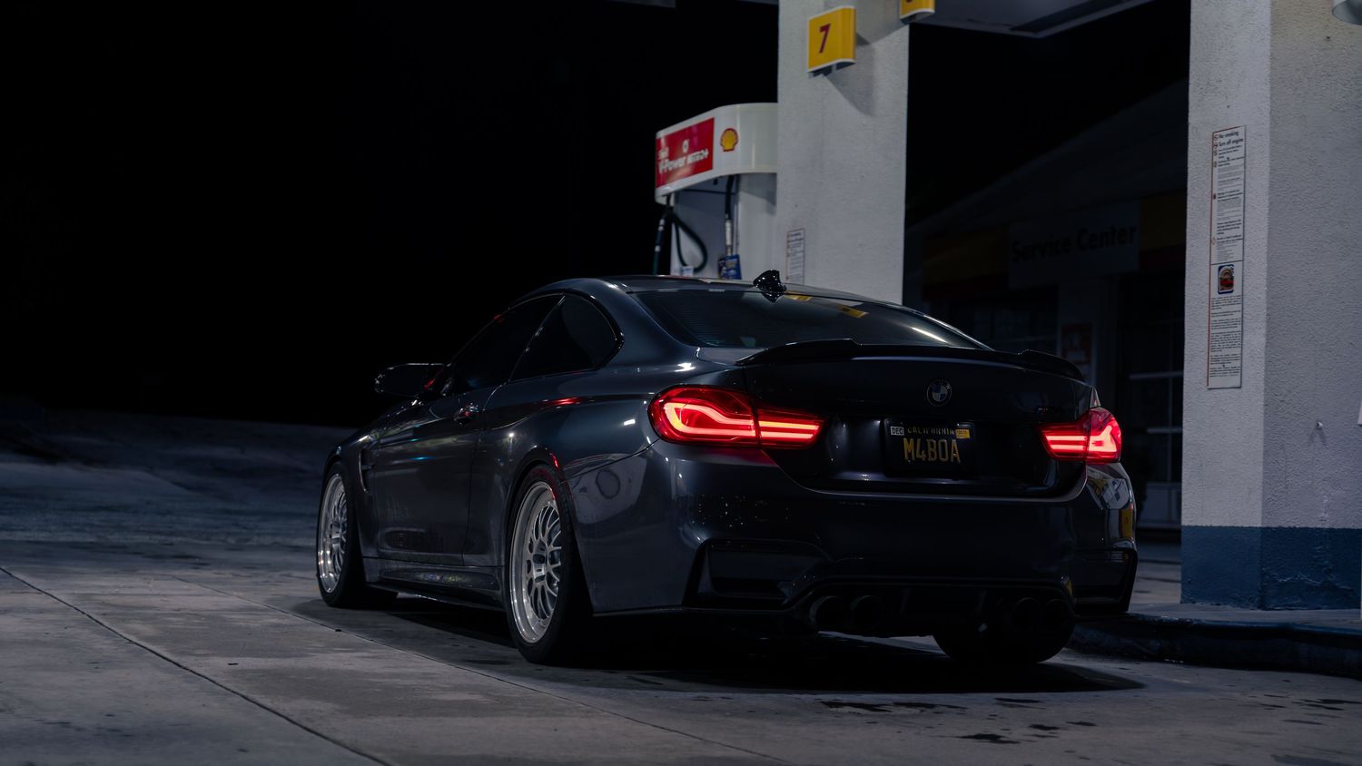 Dark parking garage interior with luxury cars displaying glowing red taillights.