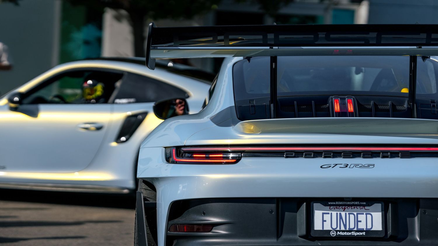 Line of modified sports cars displaying custom rear wings and performance upgrades.