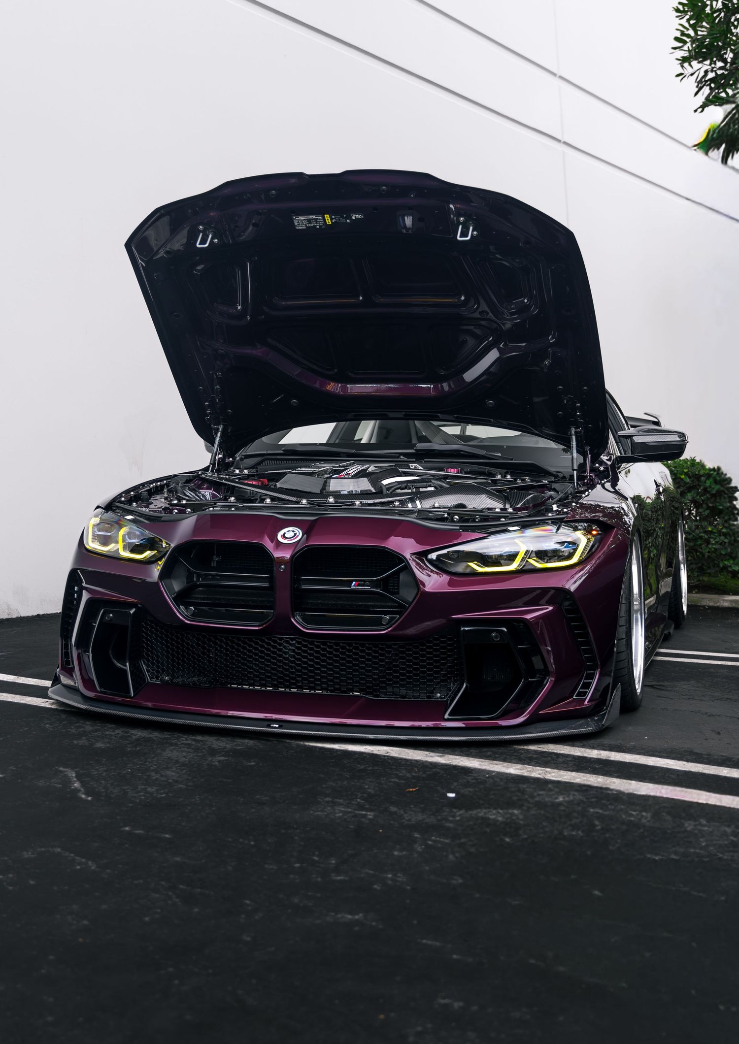 Purple BMW M4 with hood open showing engine bay modifications.