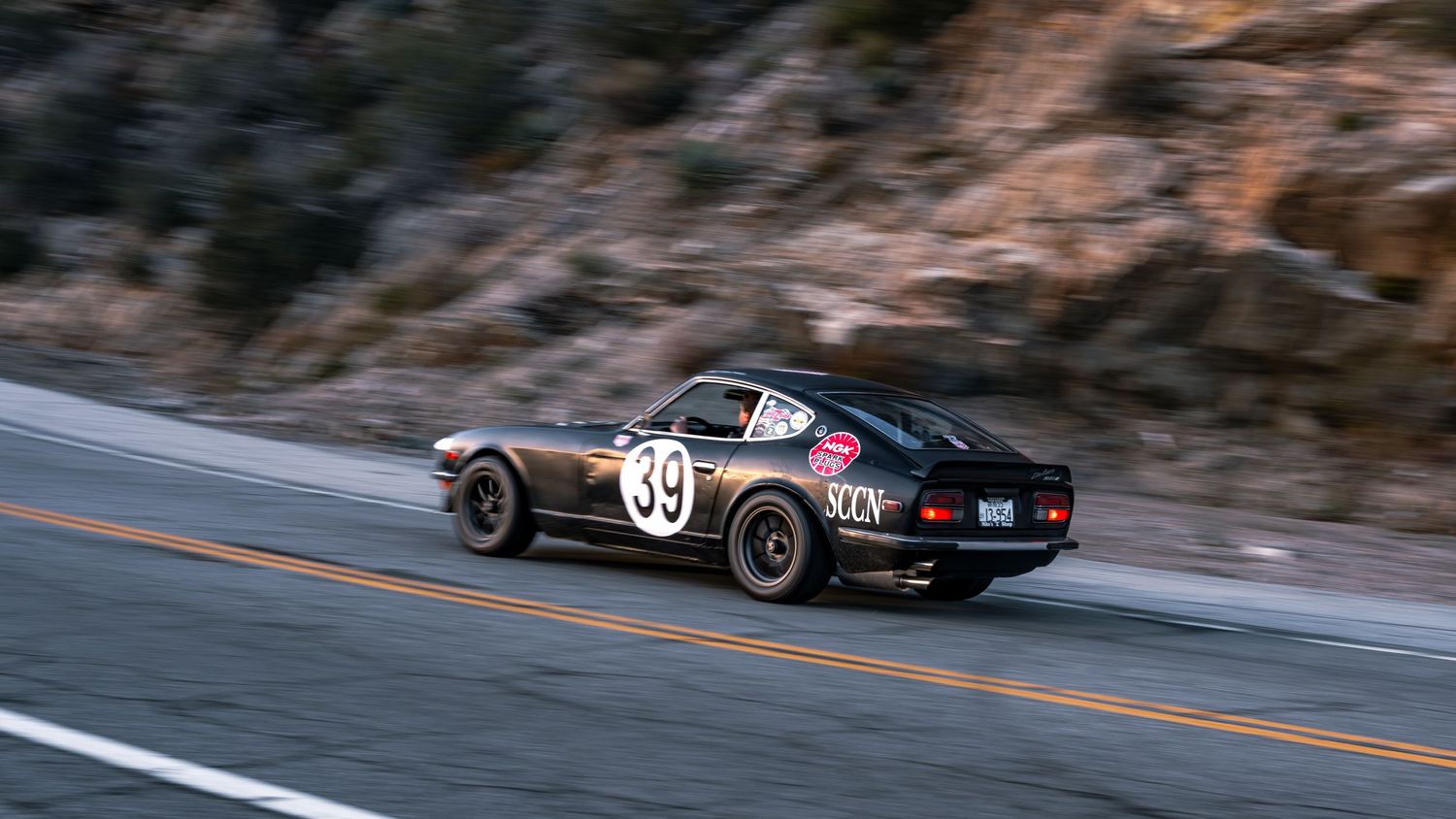 Race cars speeding through curved mountain highways at sunset.