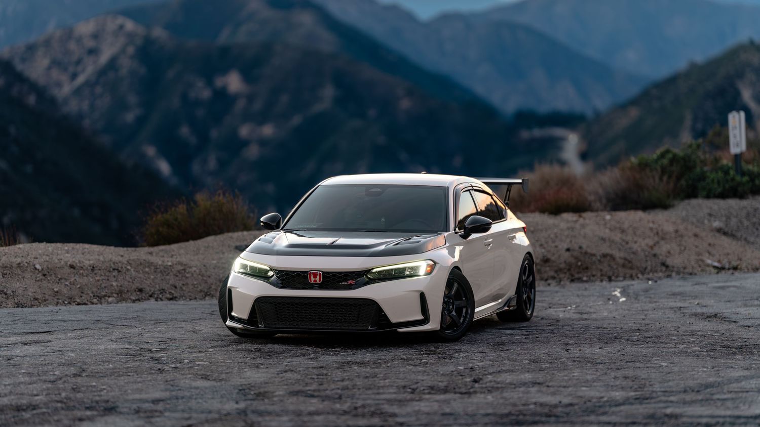 Performance cars photographed against dramatic mountain landscape backdrop.