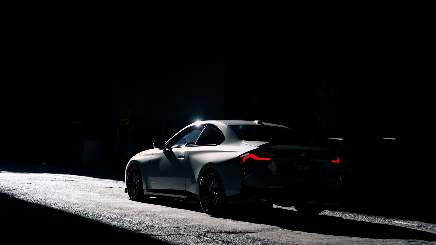 Side profile of a white BMW sports car captured in stark contrast lighting.