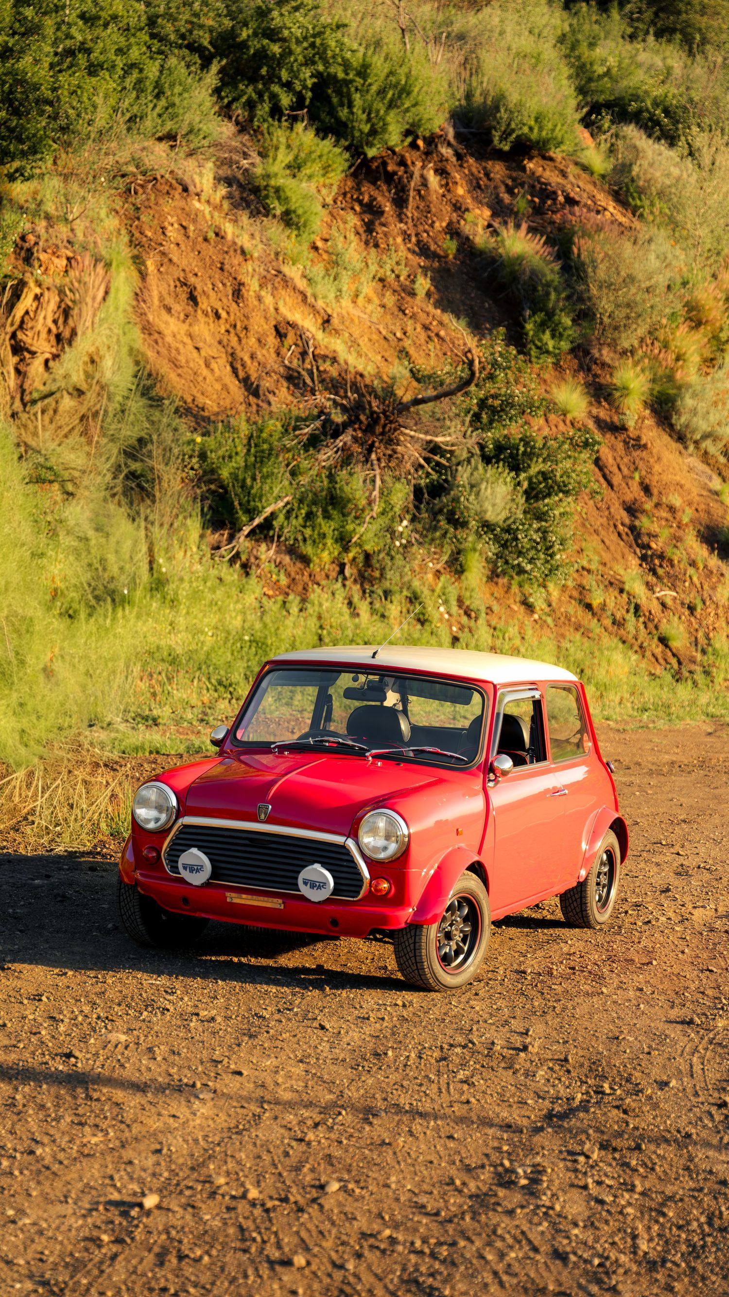 A red vintage convertible car photographed at different angles on a dirt road against a hillside backdrop.