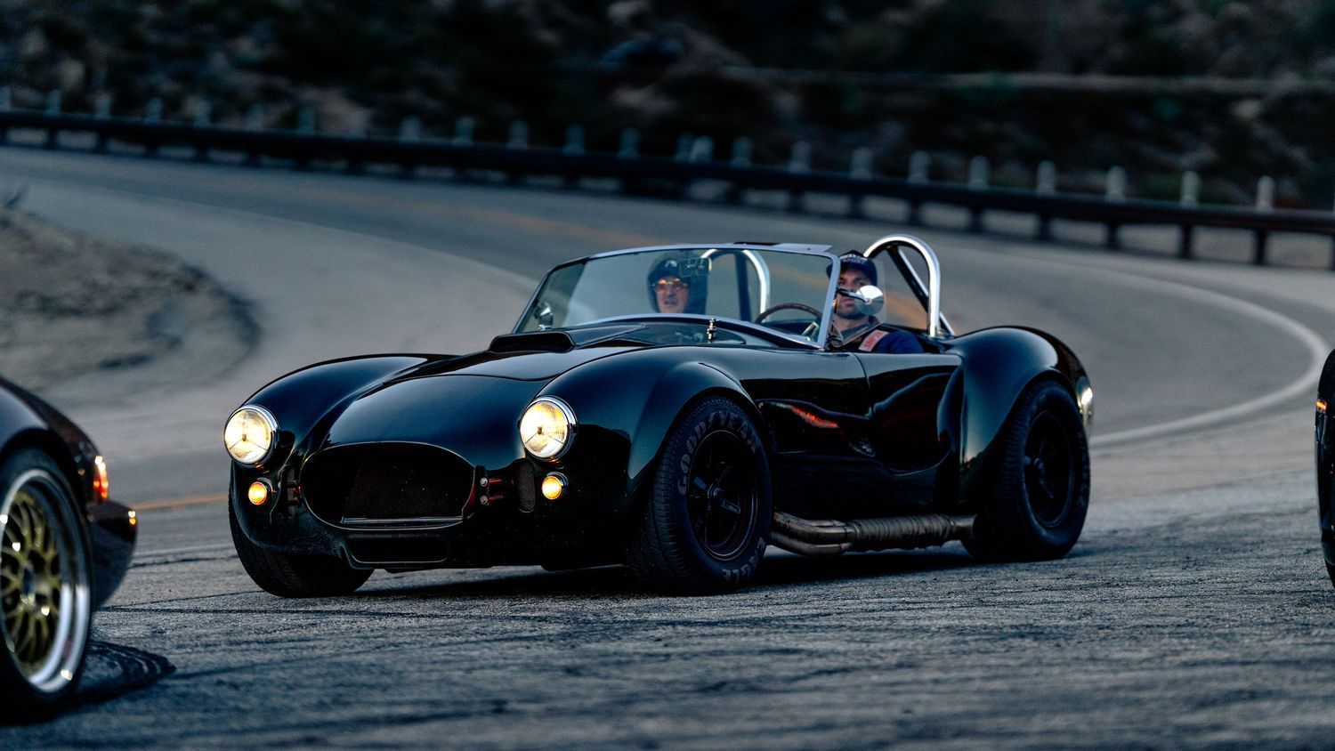 Performance cars racing around track corner during motorsport event.