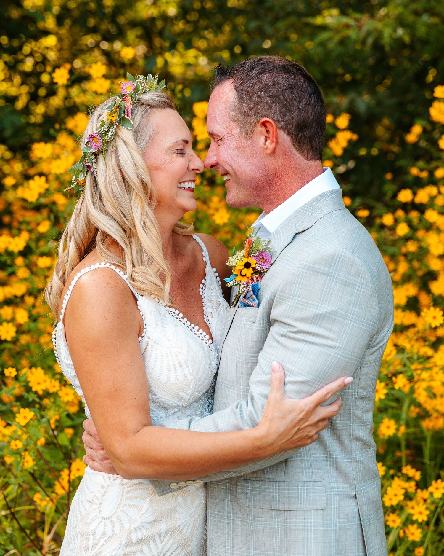 Romantic wedding couple embracing in front of vibrant yellow flowers in garden setting.wedding photography st louis photography st louis