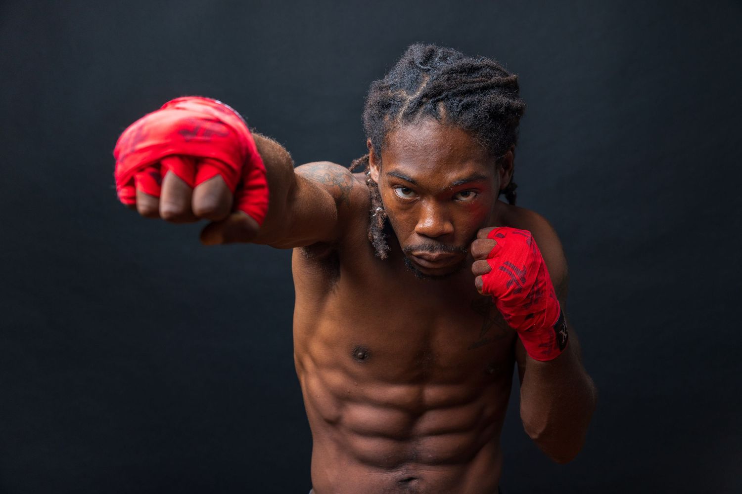 Athletic boxer with red gloves throws a powerful punch during training against dark background. photography st louis