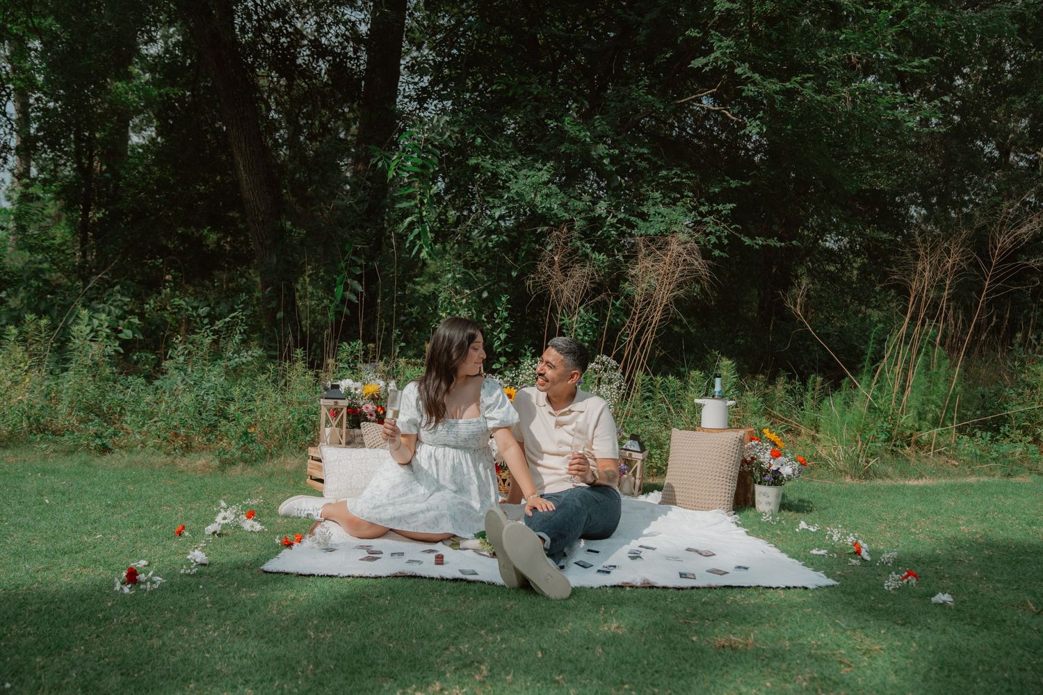 A couple lounges on a picnic blanket in a lush green park setting during a romantic outdoor date.
