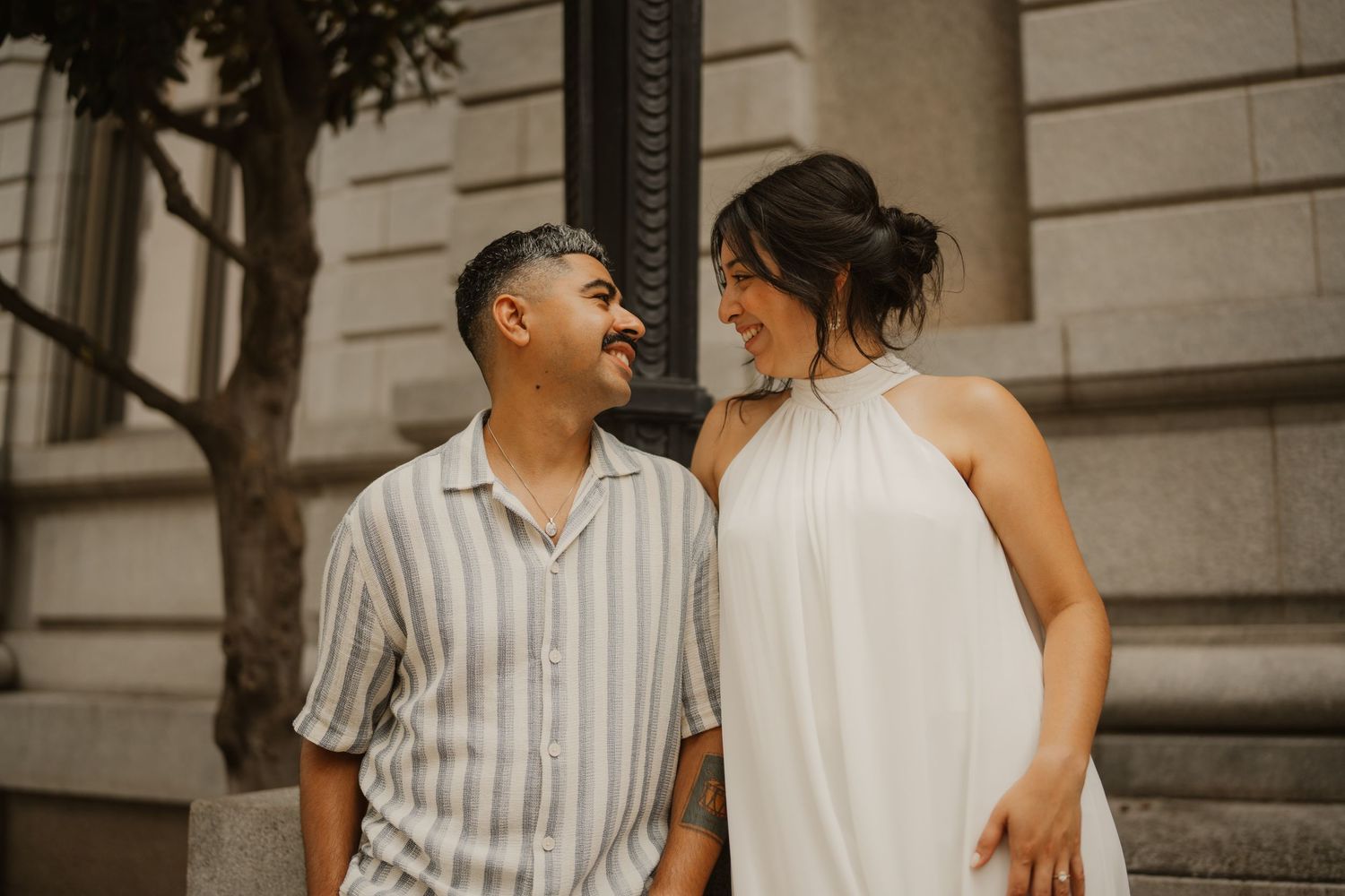 A couple shares romantic moments in a series of black and white photos on the steps of a classic building.