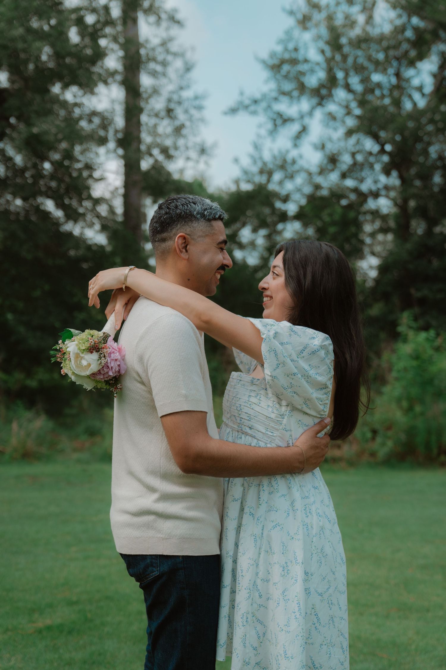 A couple dances together on a grassy lawn, with the person in a light blue dress being twirled by their partner.