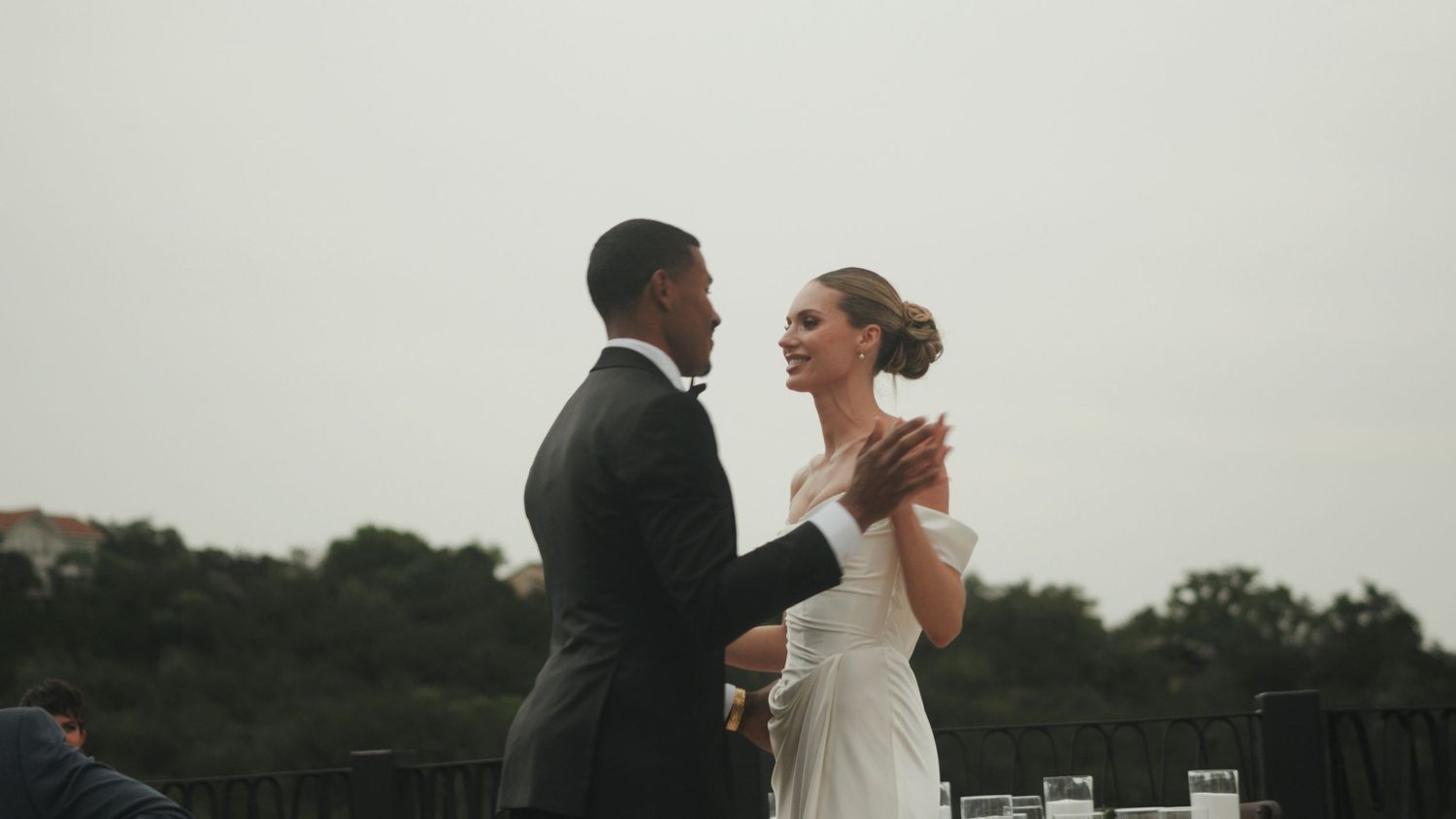 A couple dances together during their wedding reception at an outdoor venue at dusk.