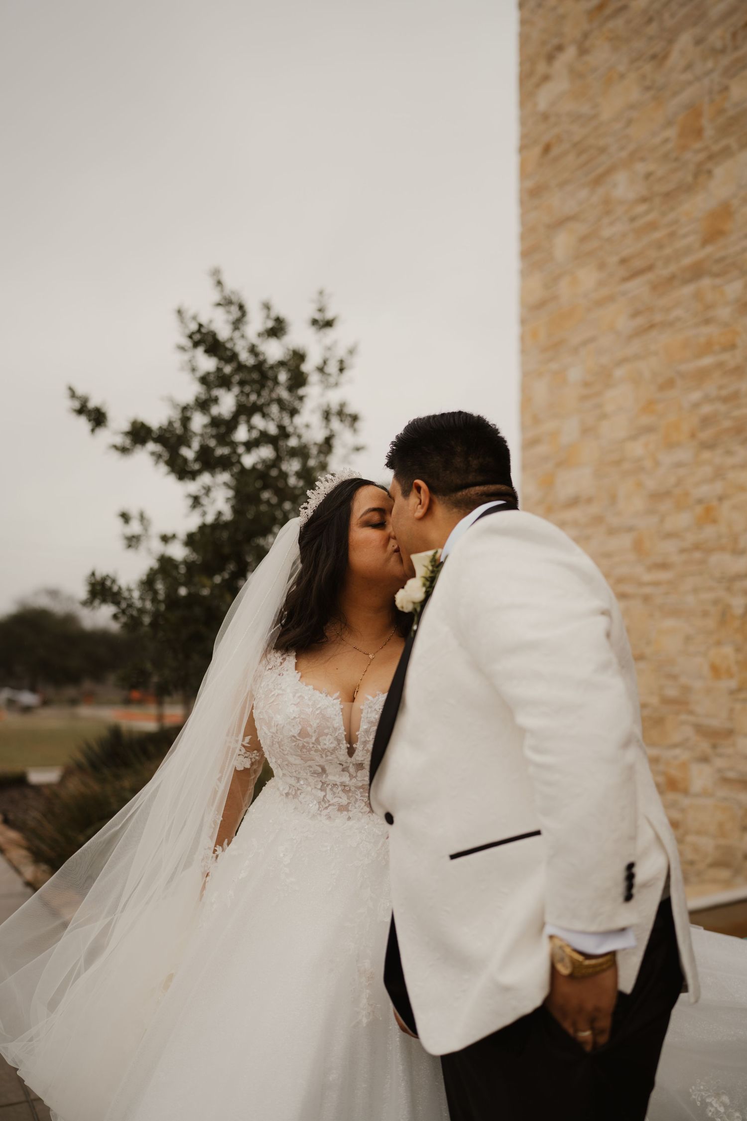 Romantic wedding moment captured against stone wall backdrop.