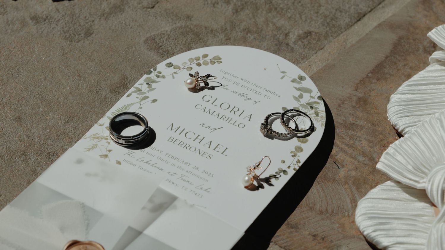 Wedding invitation and stationery details laid out on a textured surface.