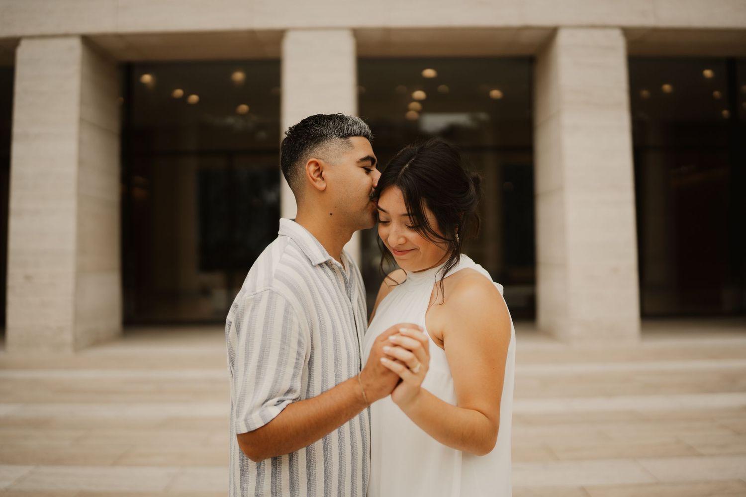 Couple shares an intimate moment in front of elegant white columns at dusk.