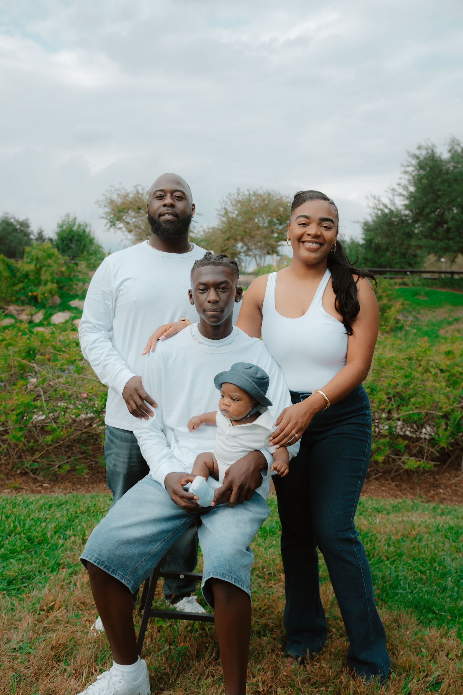 Family portrait session outdoors in a green field on a cloudy day.