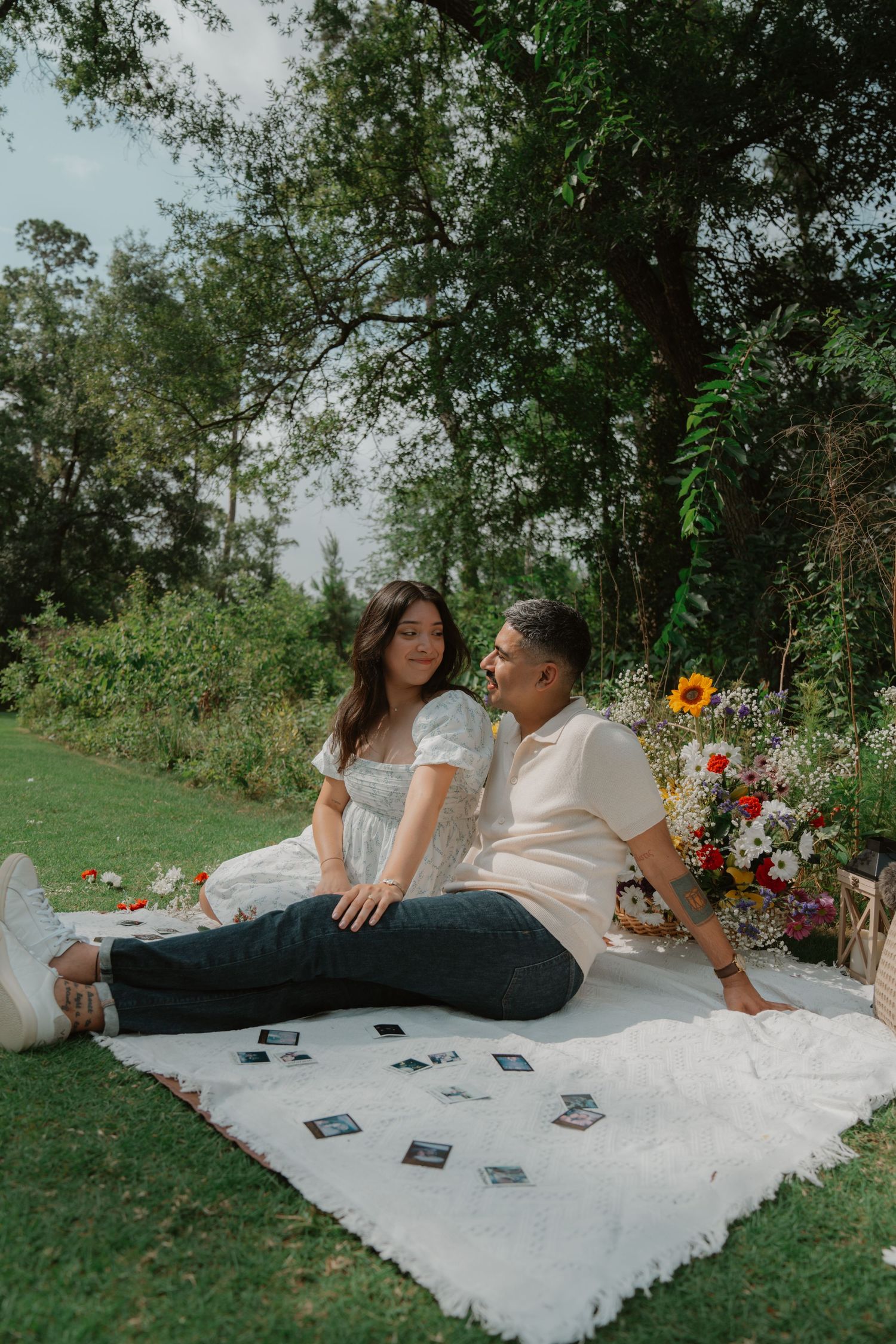 A couple relaxing on a white blanket during a romantic outdoor photoshoot.