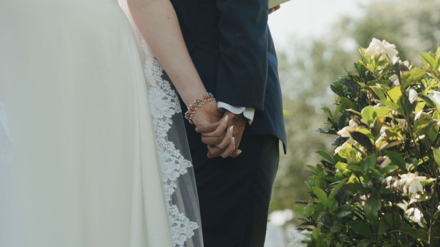 Wedding ceremony details showing formal attire and floral arrangements outdoors.