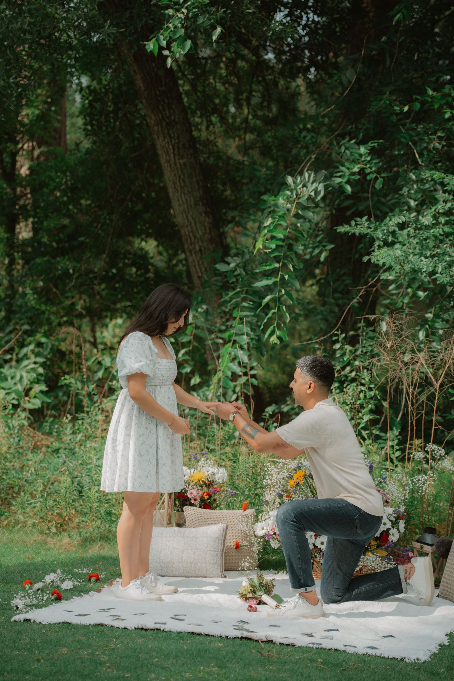 A couple enjoying a romantic picnic on a white blanket with sunflowers and decorations.