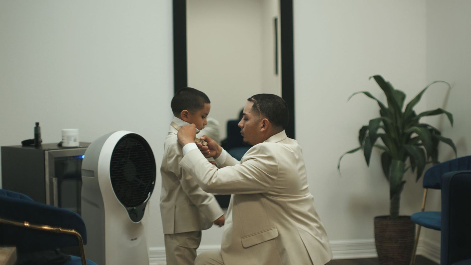Two people working together to mount a white wall shelf in a modern office space.