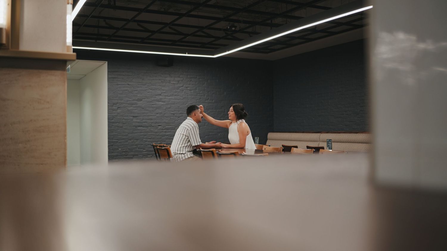 Side view of two people having a conversation in a modern room with dark walls and minimal decor.