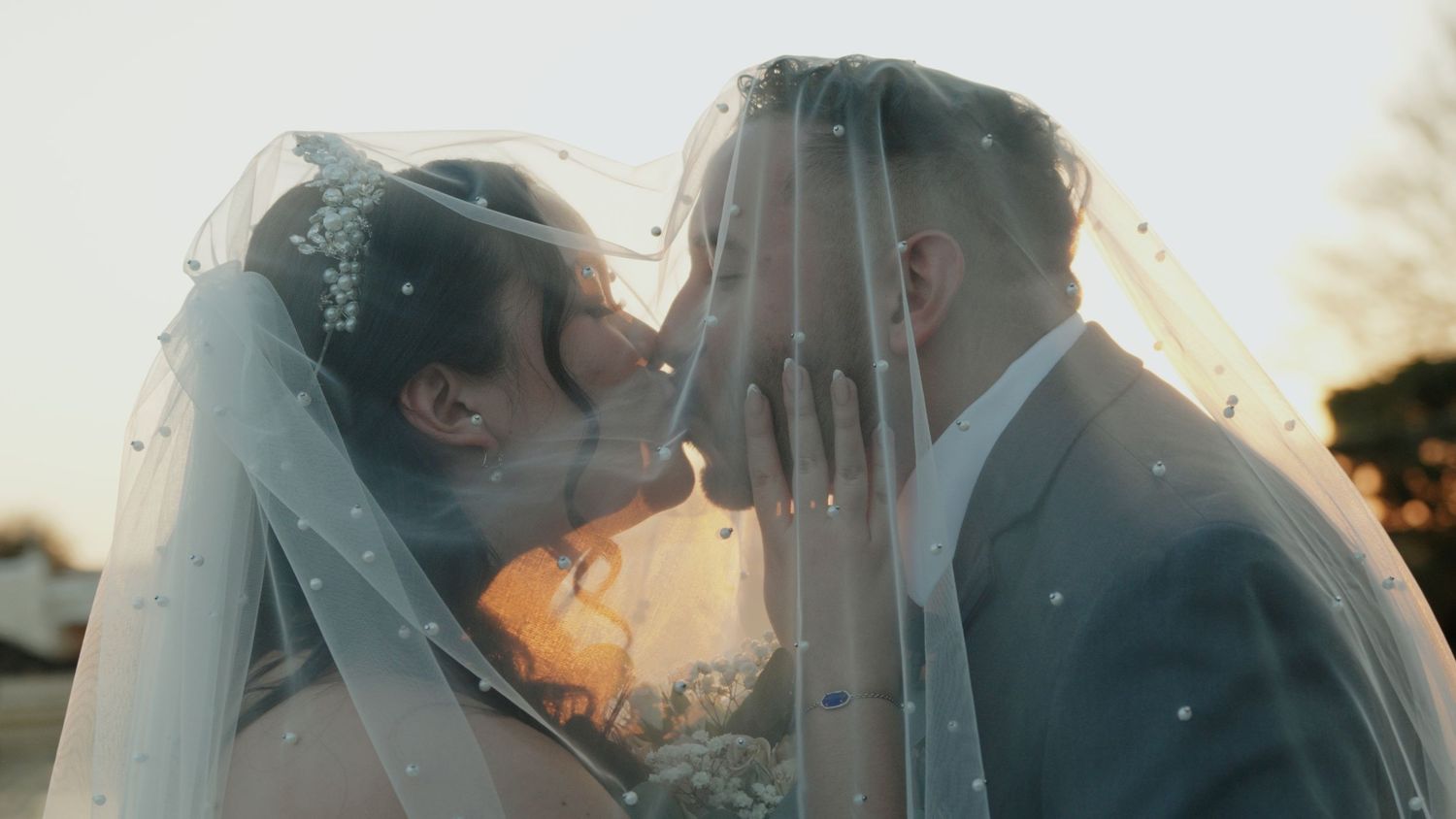 Romantic sunset wedding moment captured through a delicate veil.
