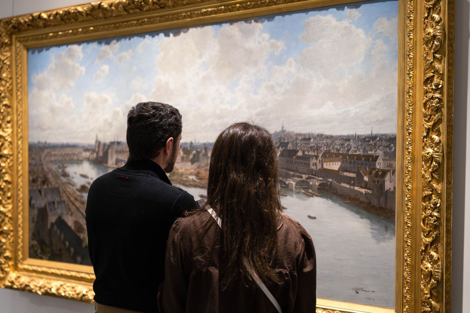 Jeune couple dans un musée qui regarde un tableau.