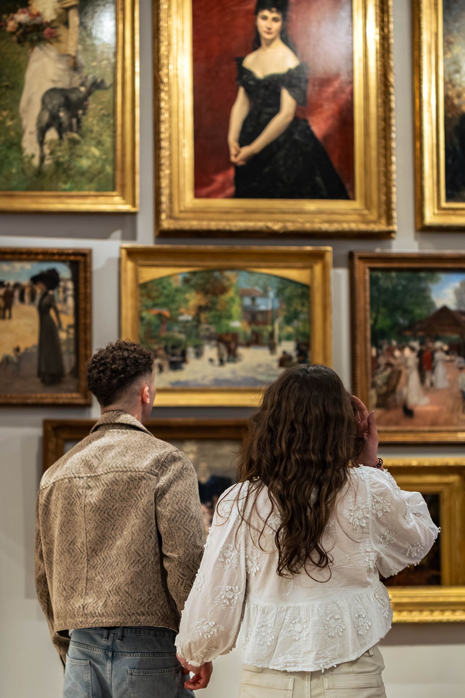 Jeune couple dans un musée qui regarde un tableau.