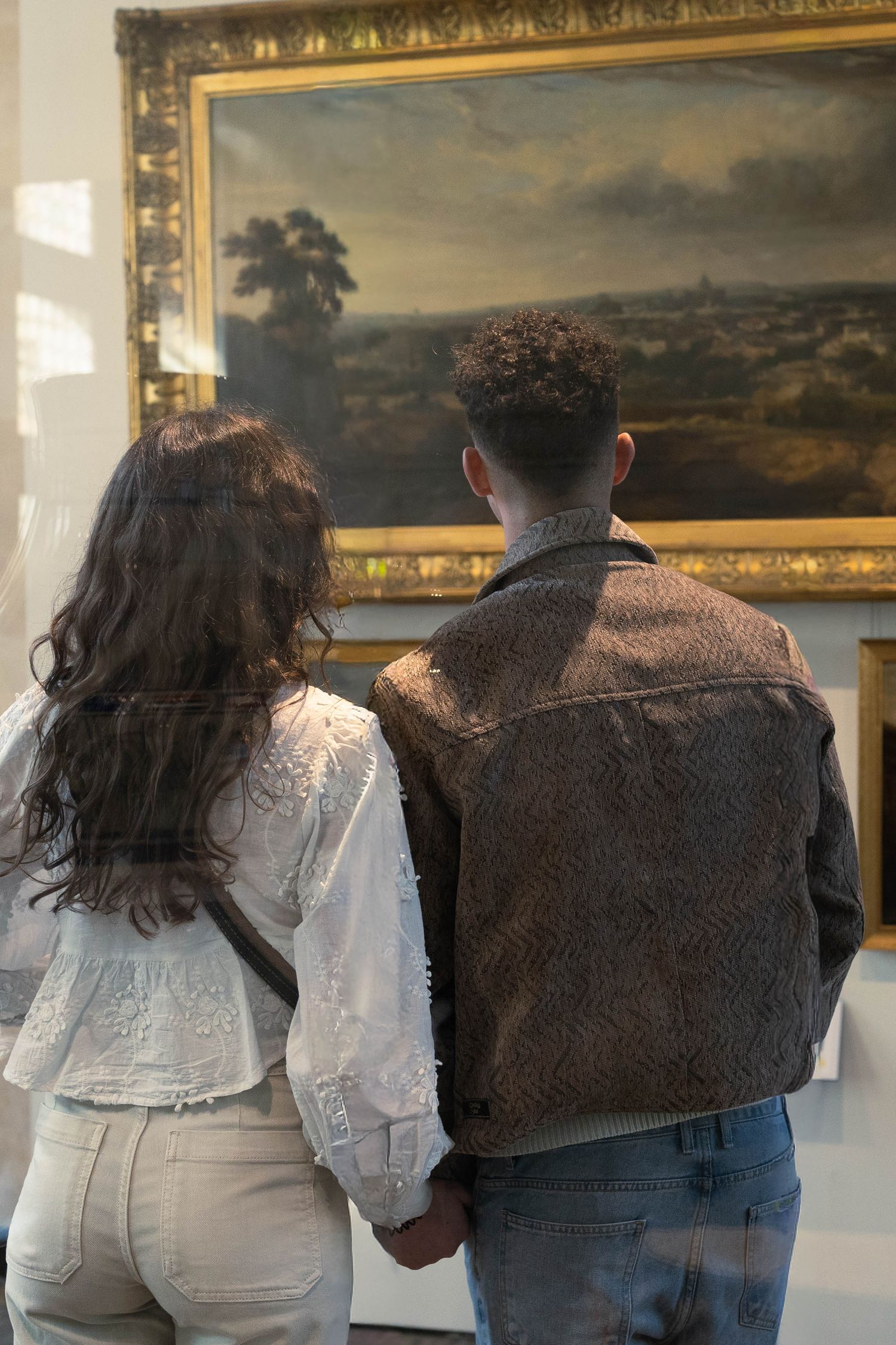 Jeune couple dans un musée qui regarde un tableau.