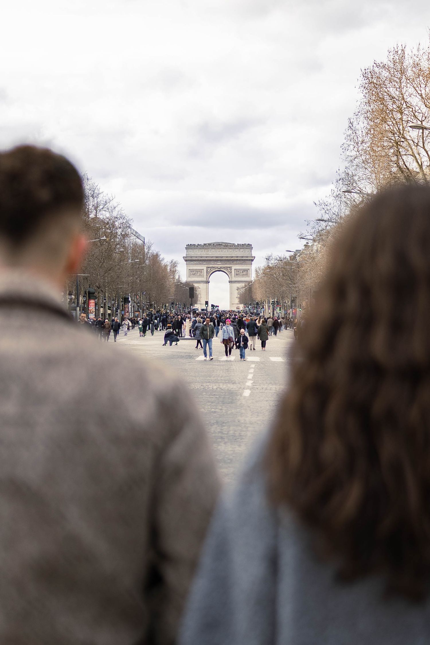 Couple qui marche main dans la main dans l'avenue des champs élisés et qui regarde l'arc de triomphe