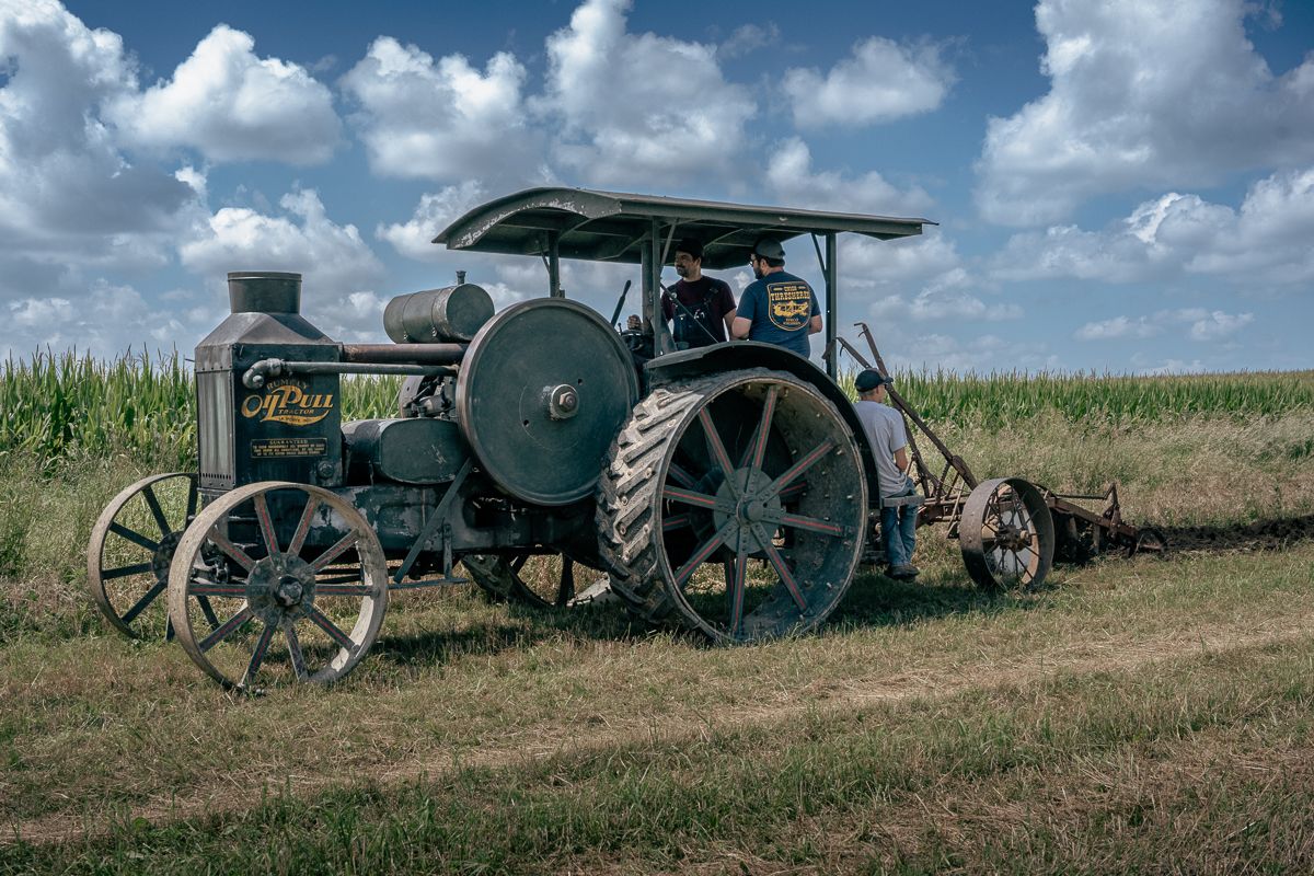 Vintage steam tractor with steel wheels displayed in rural farm setting.