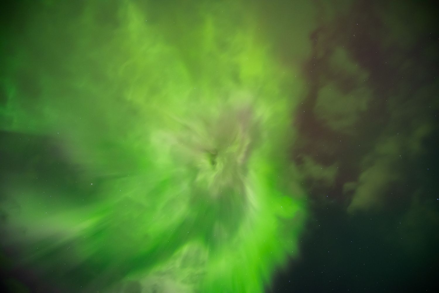Vibrant green aurora borealis lights dance across the dark night sky in a stunning natural light display.